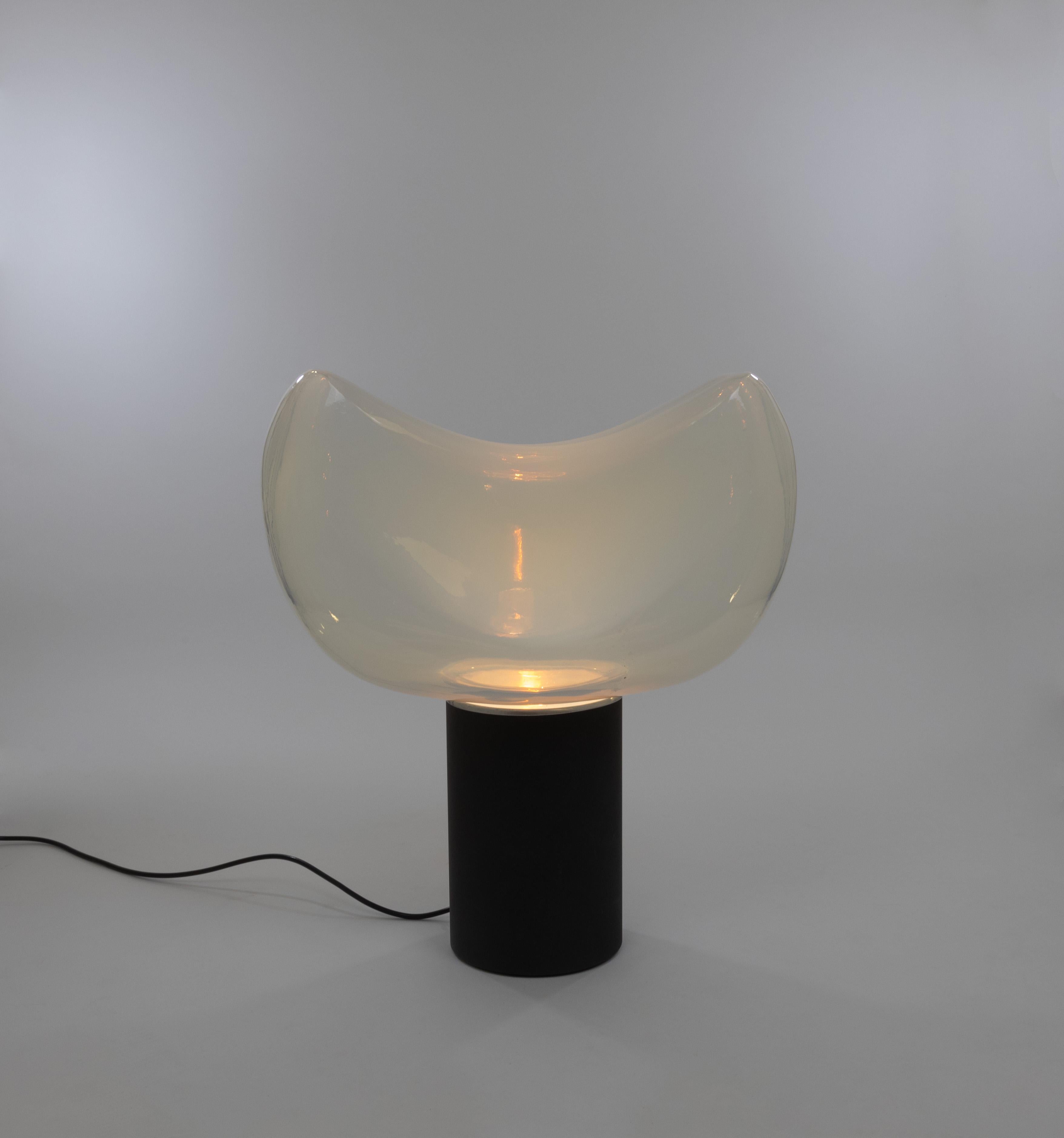 Aghia table lamp, designed by Roberto Pamio and manufactured by Leucos in the late 1960s.

The lamp consists of an opaline Murano glass shade and a cylindrical black metal base with an aluminium reflector incorporated into it. The measures of the