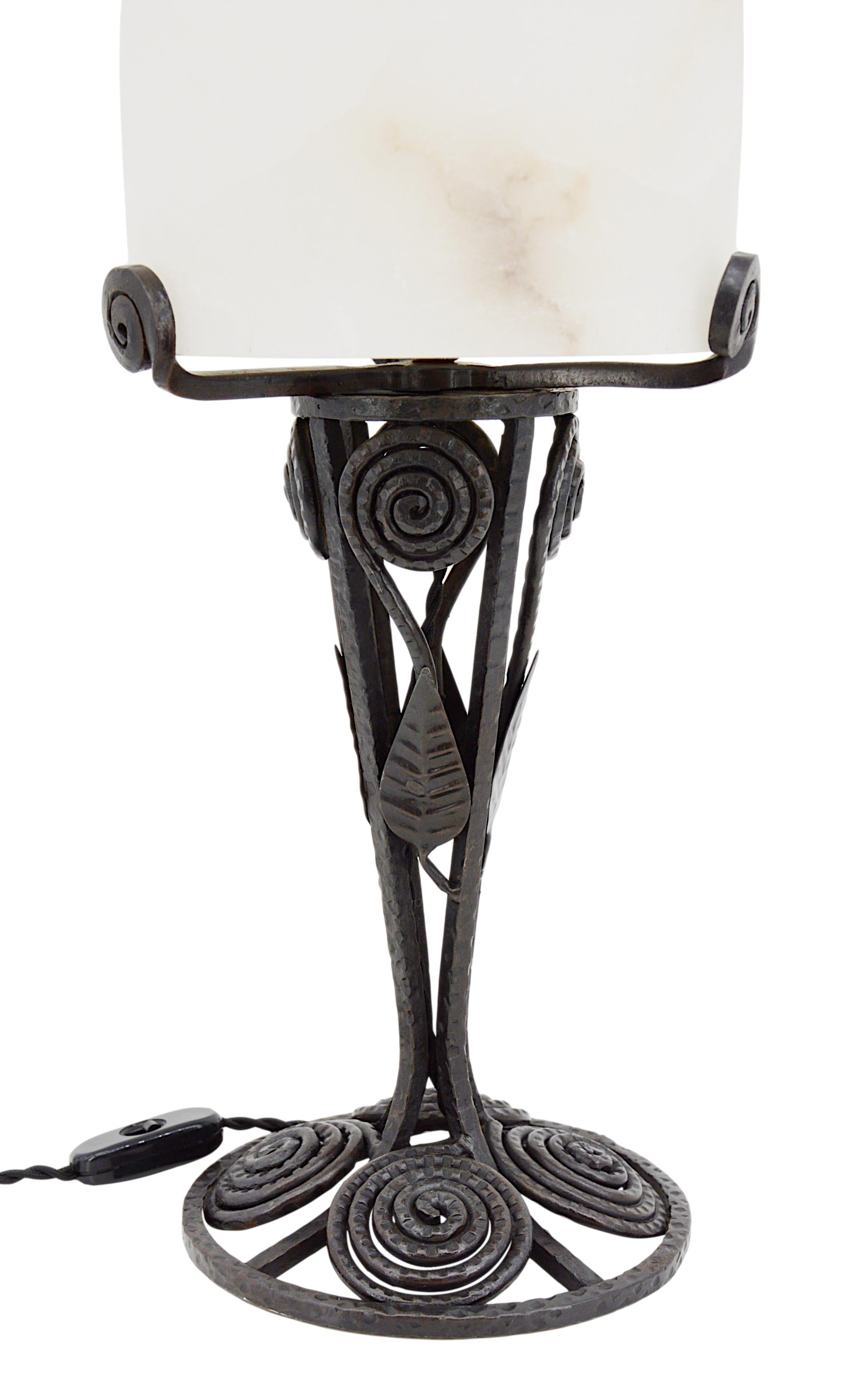 This antique French Art Deco alabaster table lamp, crafted in the 1910s, features a thick alabaster shade set upon a wrought-iron base. Old alabaster cannot be compared to new ones. Old alabaster has veins. Sometimes they can be mistaken for cracks.