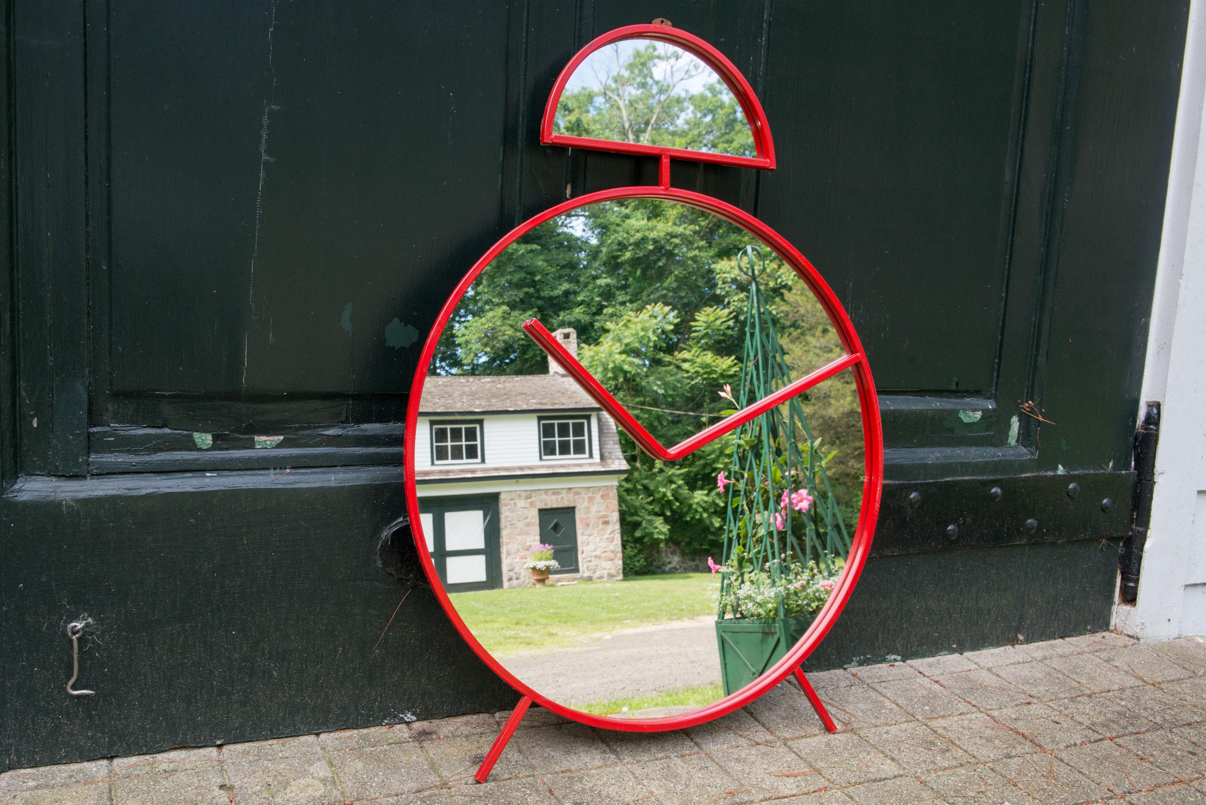 A very unusual and whimsical wall mirror in the shape of an alarm clock red lacquered metal. Made in Italy, marked Pilm.