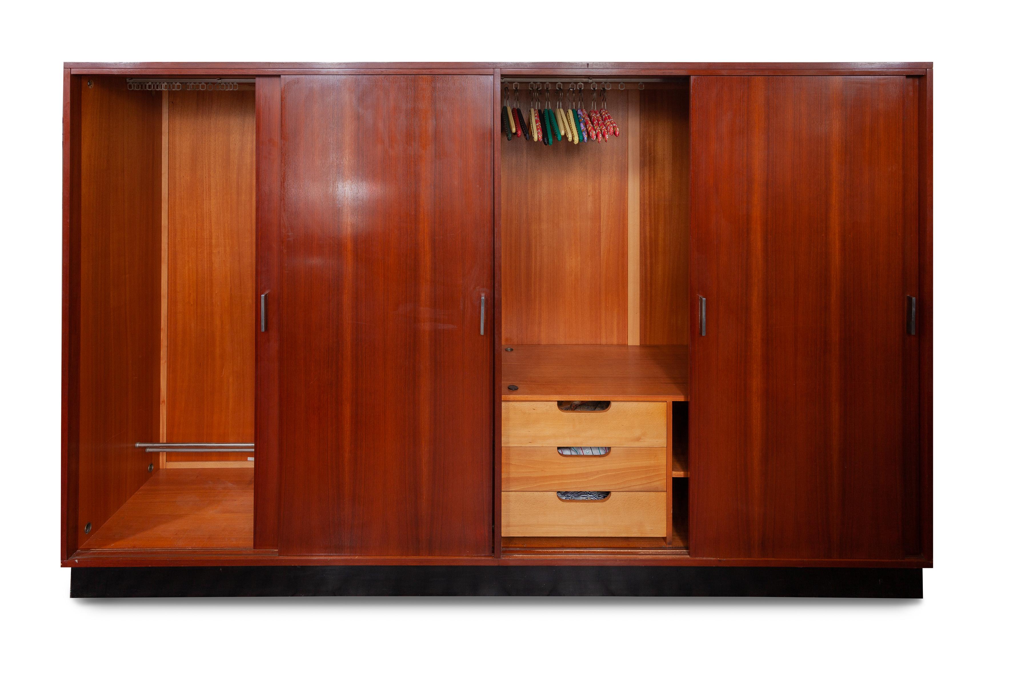 Vintage midcentury wardrobe by Alfred Hendrickx for Belform Belgium. Beautiful warm exotic wood frame on floating black platform base. Silver metal handles. The sliding doors open to reveal generous hanging space, two adjustable shelves and three