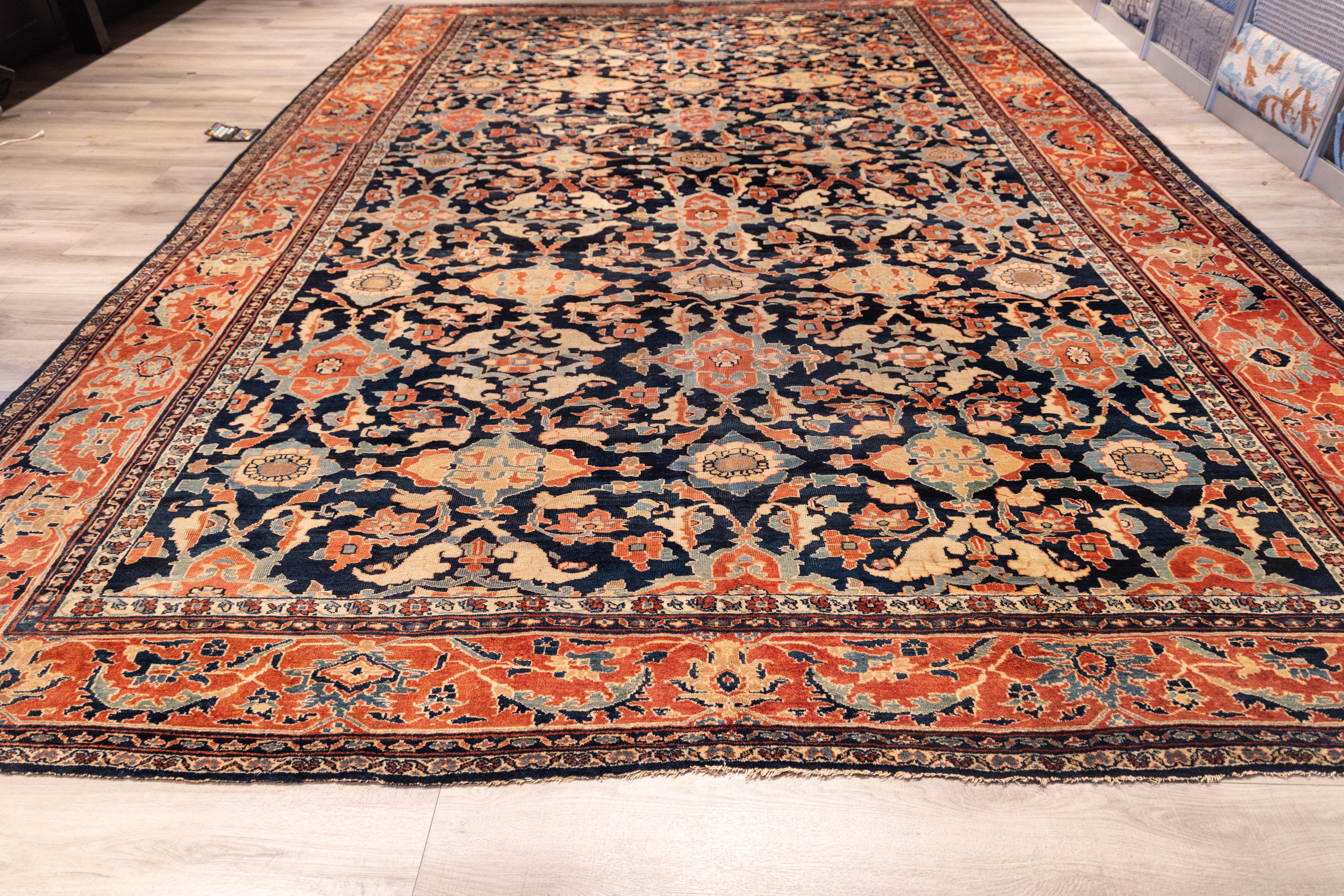 A Large refined Ziegler Mahal rug featuring an allover lattice of palmettes and floral motifs across a deep indigo field. The composition balances symmetry and spontaneity, with coral, ivory, and soft blue tones creating elegant contrast. The wide