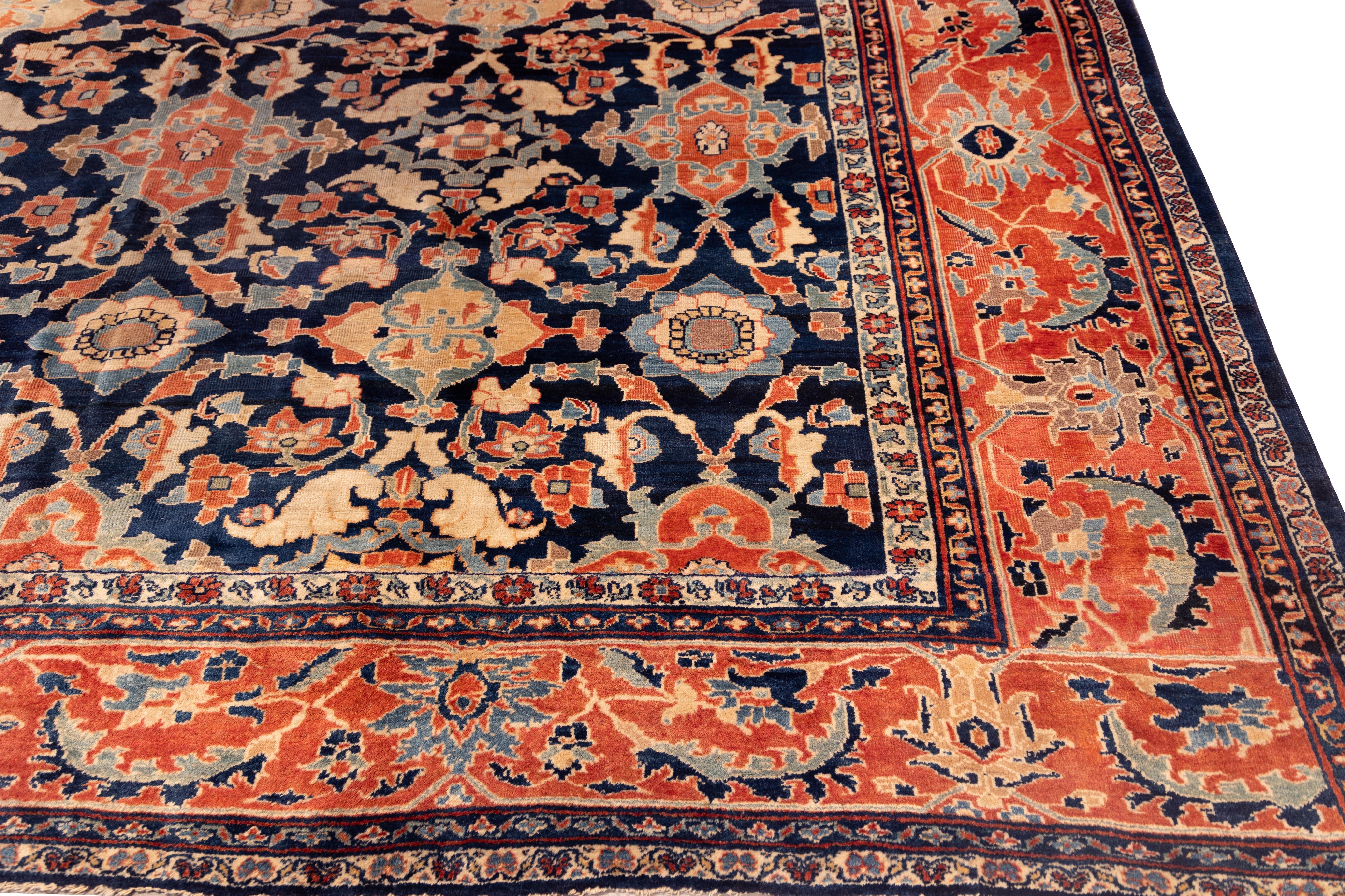 A Large refined Ziegler Mahal rug featuring an allover lattice of palmettes and floral motifs across a deep indigo field. The composition balances symmetry and spontaneity, with coral, ivory, and soft blue tones creating elegant contrast. The wide