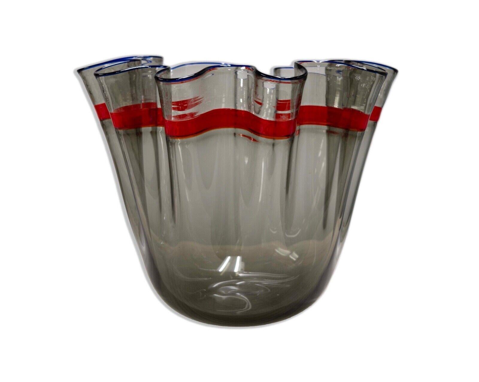 This striking Alvise handkerchief bowl, a masterpiece from the 1980s, features a unique fazzoletto design that mimics the elegant drape of a handkerchief. The vessel is crafted with a smoky translucent glass, adorned with a vivid red stripe that
