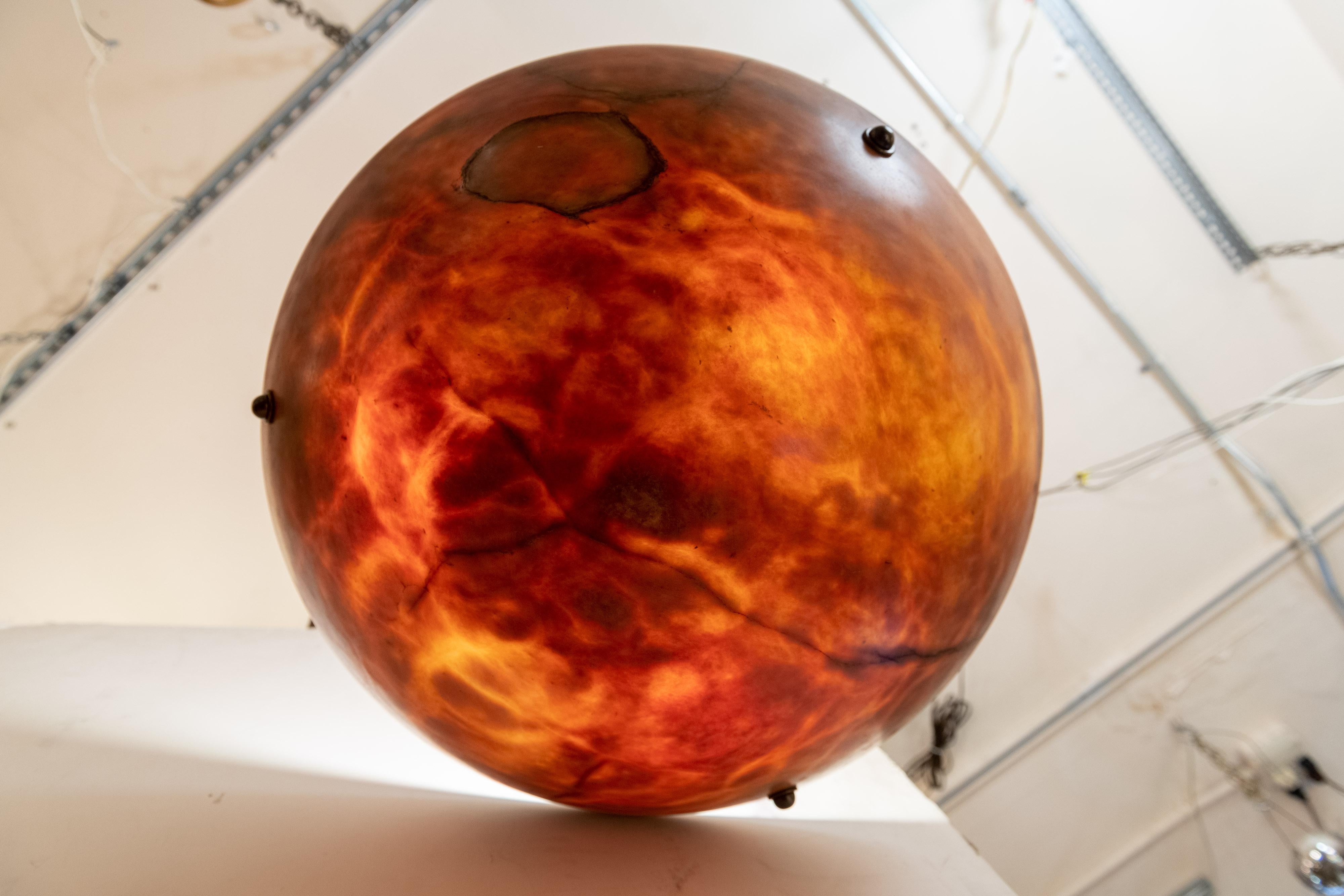 Alabaster pendants are one of our best selling areas of antique lighting, and here we are offering a big 24'' diameter pendant. Mostly amber with some unusual black fissures and veins. 3 porcelain sockets and newly wired to handle 100 watt bulbs if