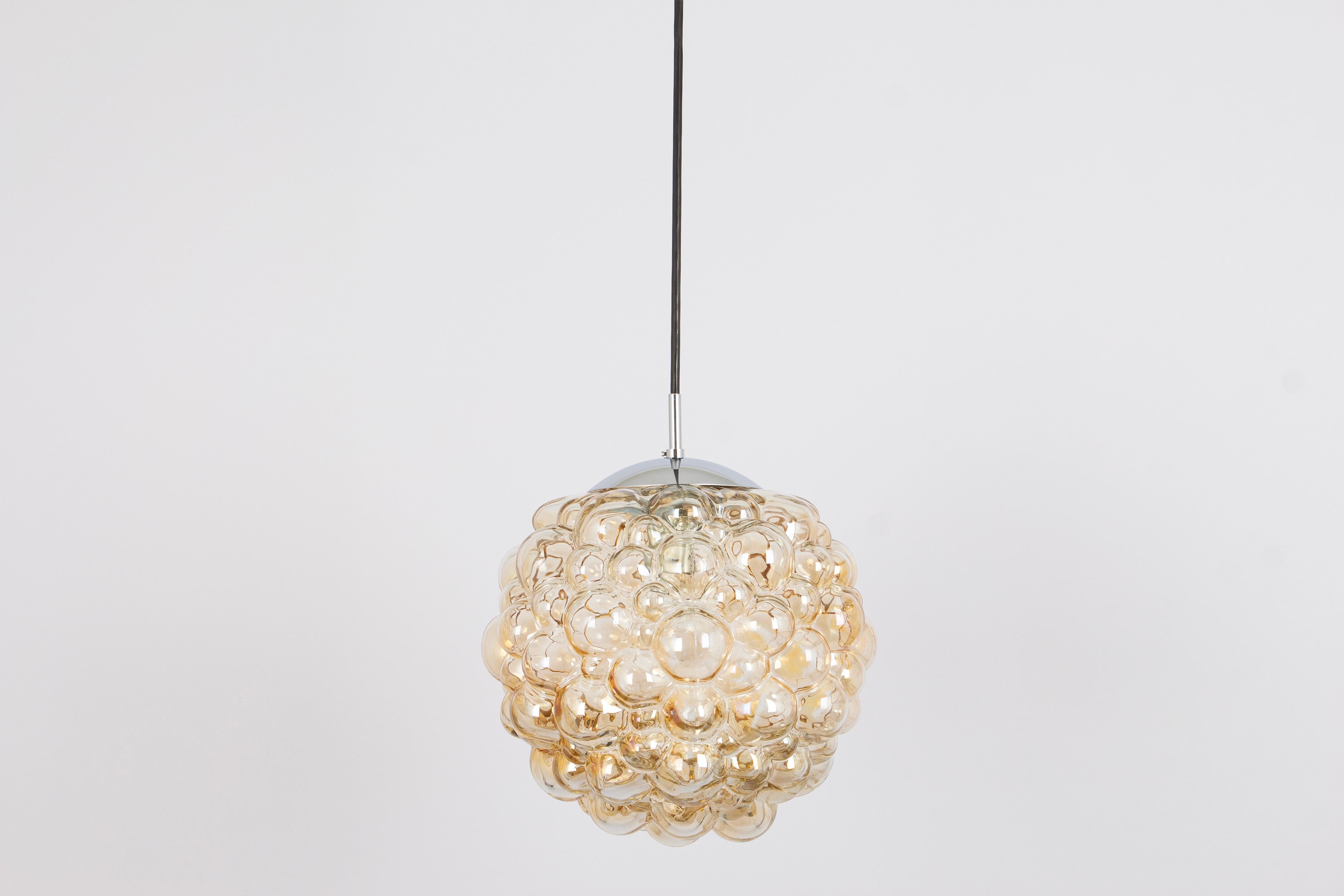 A round bubble glass pendant with light smoke tone designed by Helena Tynell for Limburg, manufactured in Germany, circa the 1970s
What sets this pendant light apart is its captivating bubble texture within the glass. Tiny bubbles are intentionally