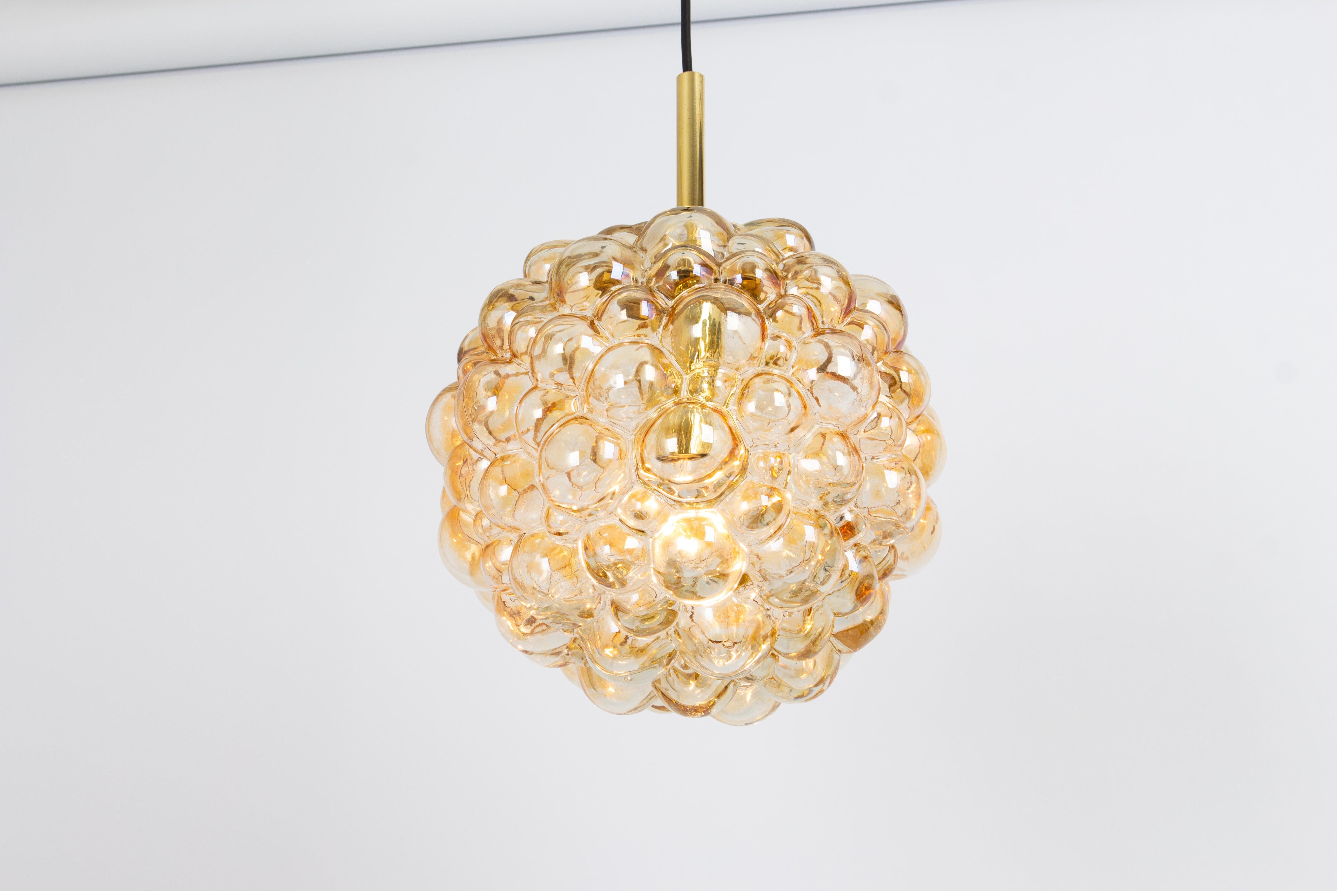 A round bubble glass pendant with light smoke tone designed by Helena Tynell for Limburg, manufactured in Germany, circa the 1970s
What sets this pendant light apart is its captivating bubble texture within the glass. Tiny bubbles are intentionally