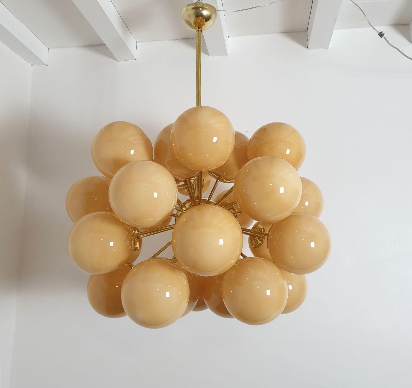 Very large Mid-Century Modern Amber Murano globes Sputnik chandelier, Italy circa 1990s.
The huge chandelier is made of brass mounts and 30 Murano glass globes, each nesting one light.
The glasses are translucent, in a warm amber color.
The Italian