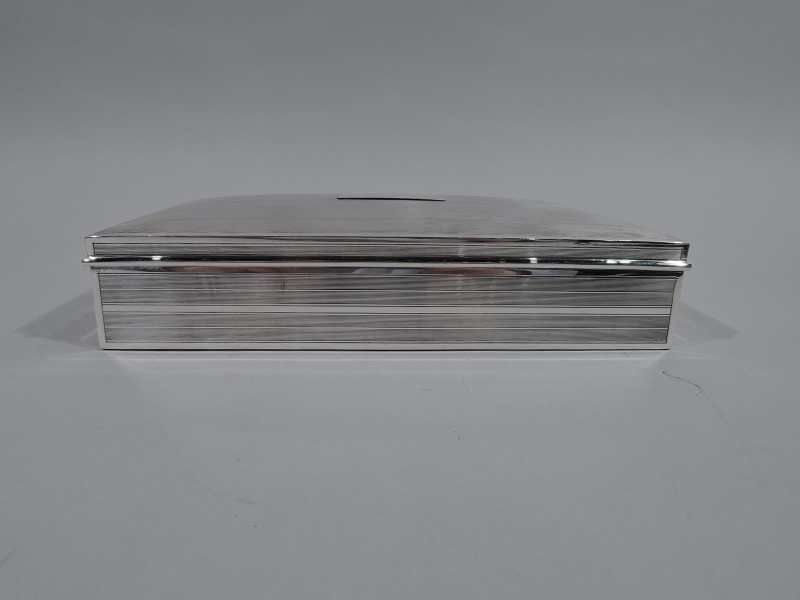 Large American Art Deco sterling silver box. Rectangular with straights dies, and curved and hinged cover. Engine-turned linear ornament on cover and sides: 2 groups of fine lines alternating with 1 wide plain line. Central rectangular mono plate