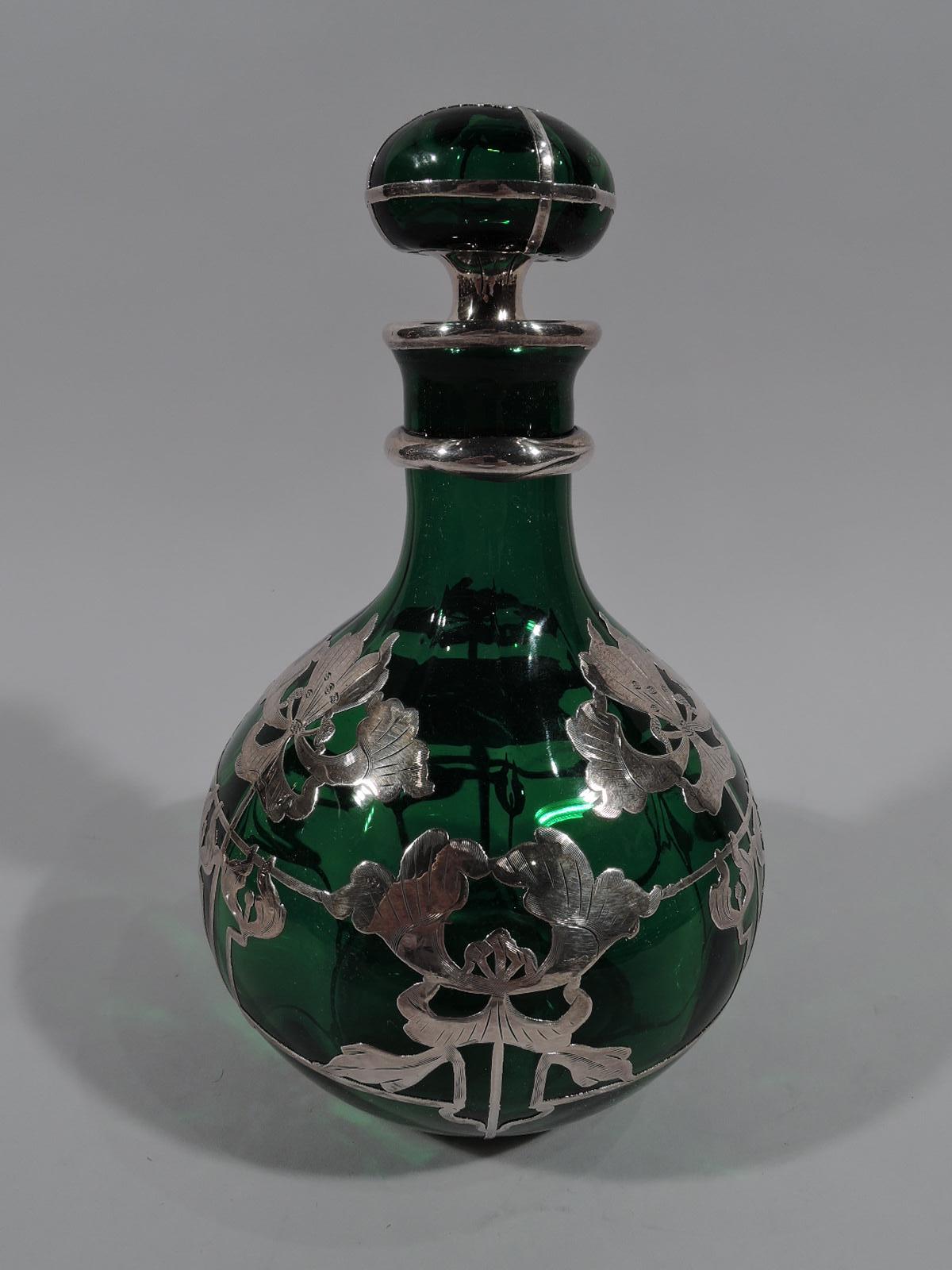 Turn of the century American Art Nouveau green glass silver overlay perfume. Ovoid with flattened ball stopper. Semi-abstract flowers and curvilinear lines overlapping 2 thin hoops. Neck spool form with silver rim collar and thick knop, and subtle