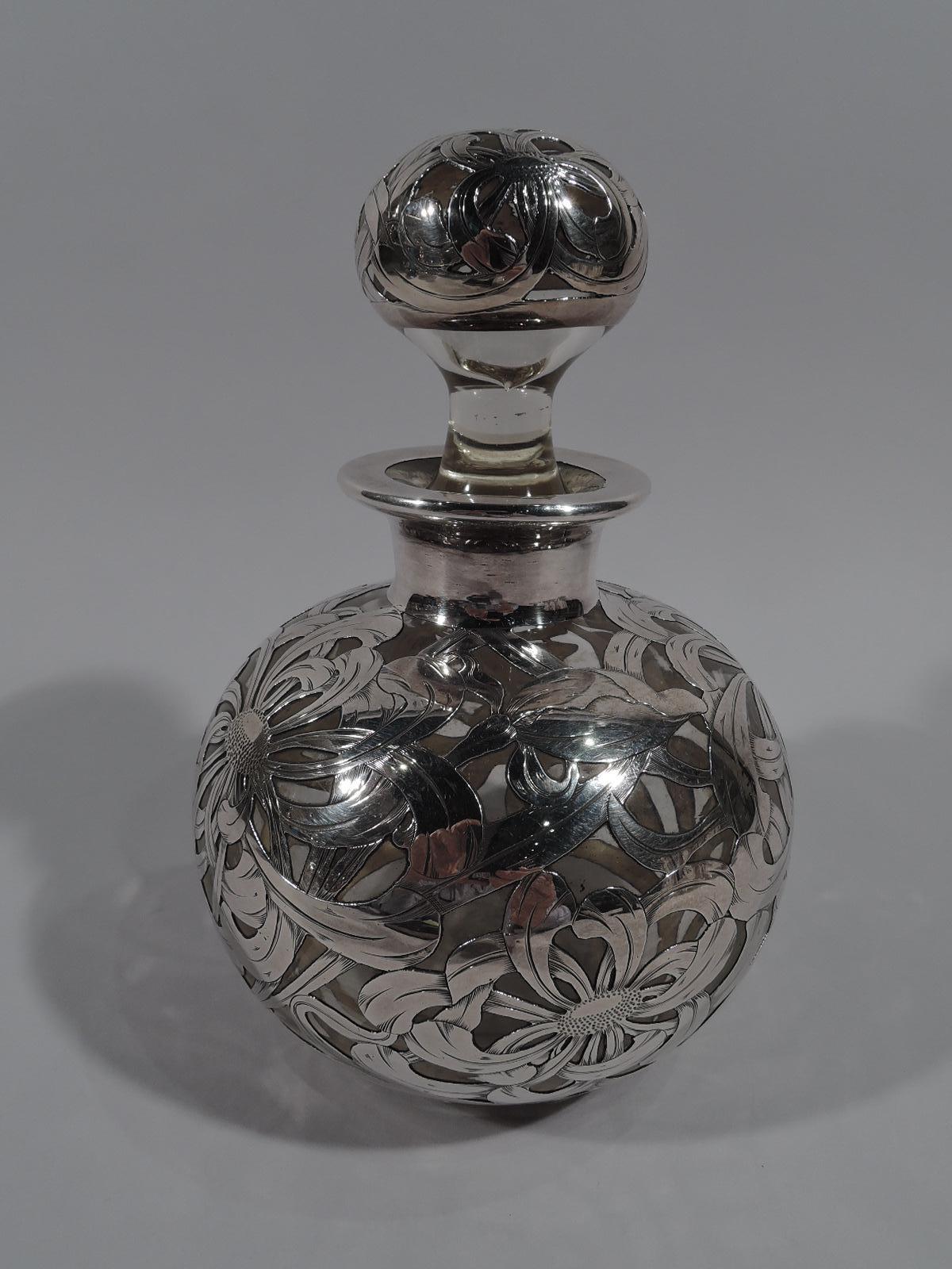 Large turn-of-the-century American Art Nouveau glass cologne bottle with engraved silver overlay. Globular; short neck and everted rim in collar. Ball stopper. Dense overlapping and interlaced overlay in form of flower heads and tendrils. Glass is
