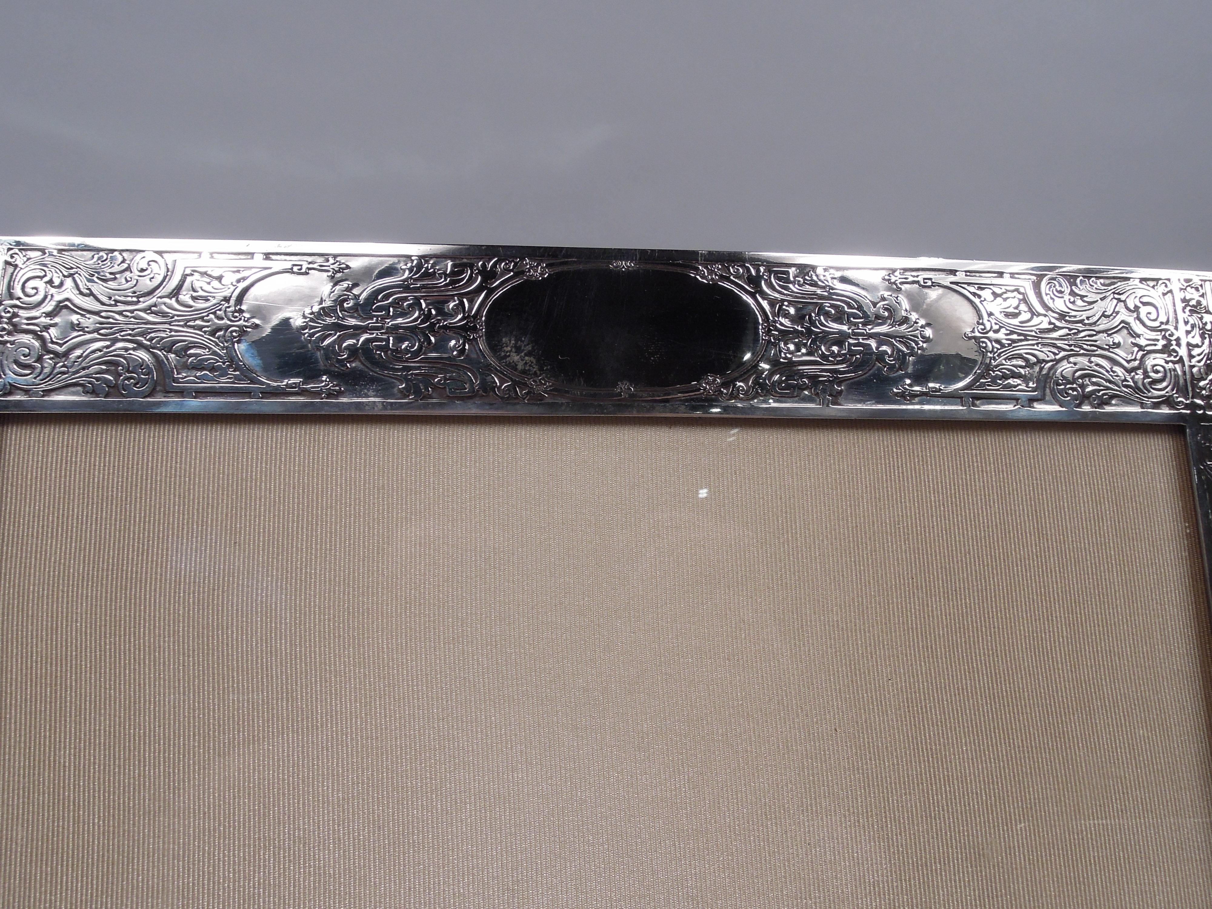 Large Edwardian Classical sterling silver picture frame. Made by The McChesney Co. in Newark, ca 1910. Rectangular window in same surround with beautiful acid-etched ornament on front: Leaf-and-dart border with corner flowerheads and ornamental