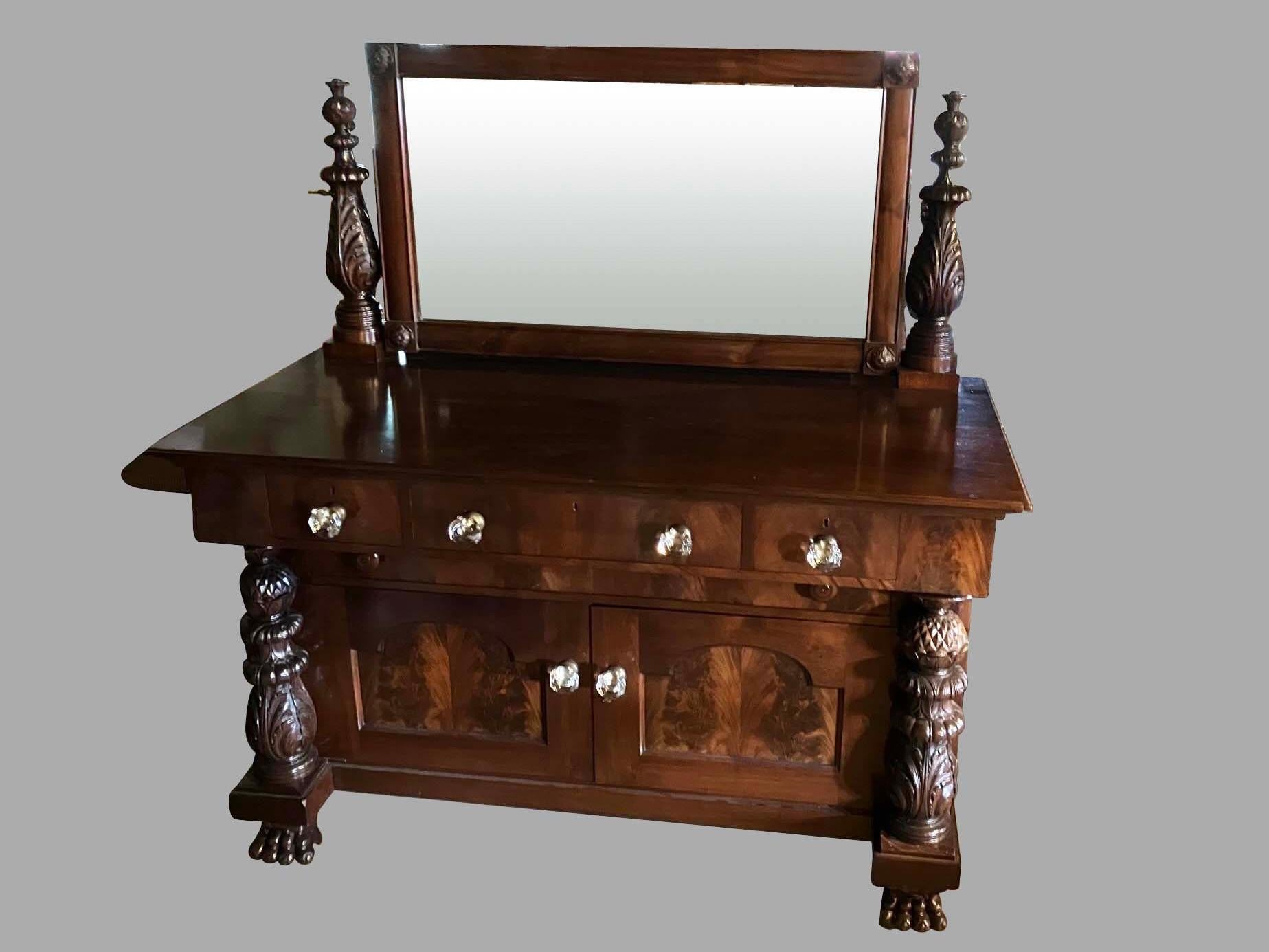 A substantial American Empire Revival period mahogany dressing chest the top with a molded edge and an attached adjustable mirror supported by well-carved standards. The lower case is fitted with 3 deep drawers retaining their original oversize
