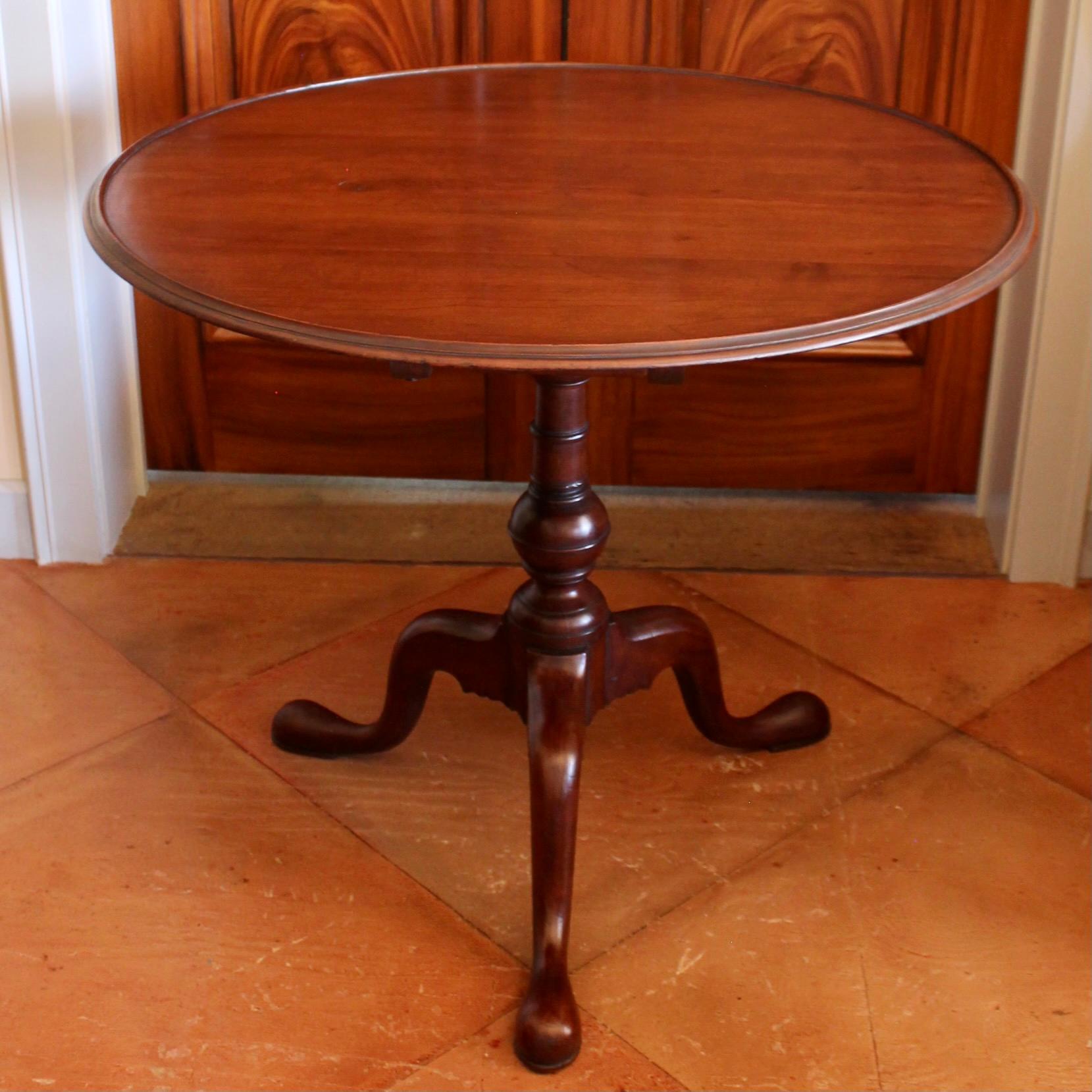 A handsome medium toned cherry three board top with a tight moulded edge, resting on a baluster base with multiple turnings, most notably the banded sphere anchoring the standard. The birdcage has a nicely formed pin and separate catch plate. Robust