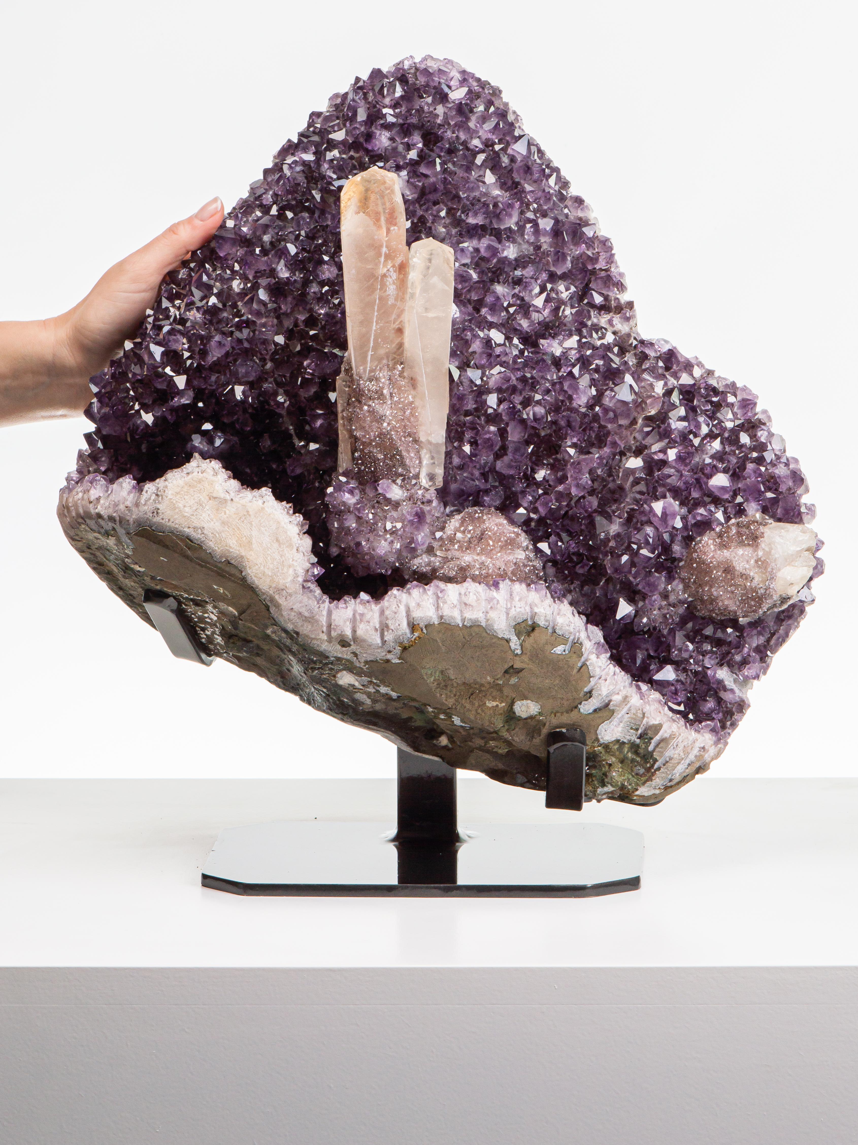 Two calcite “towers” grace the centre of this impressive piece, which also
has large peaked amethyst crystals and quartz and goethite covered calcites.
The exterior has been kept in its rough state, contrasting beautiuflly.
With the reflective