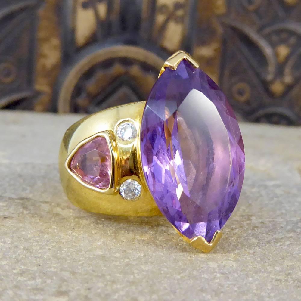 This stand out contemporary ring holds one large Amethyst stone in the centre with a triangular shaped Pink Tourmaline at wither side. Between the gemstones sit four Diamonds weighing a total of 0.25ct. All held in place with 18ct Yellow Gold with a
