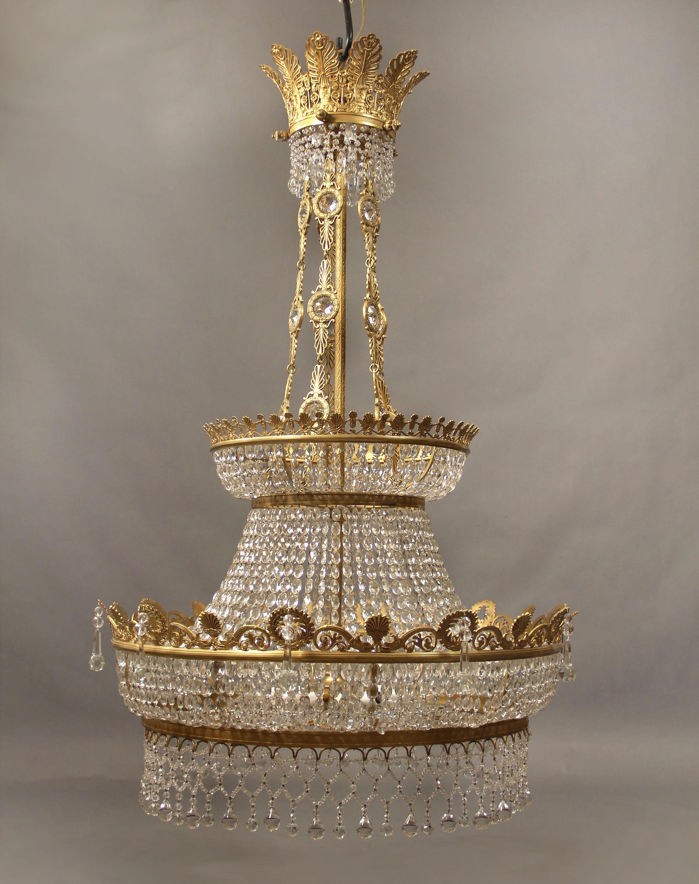 A large and beautiful late 19th century gilt bronze and crystal twenty-light Russian Empire style chandelier.

With two tiers, each fitted with interior lights, typical Empire bronze designs, drop crystal and plumes as the crown.

If you are looking