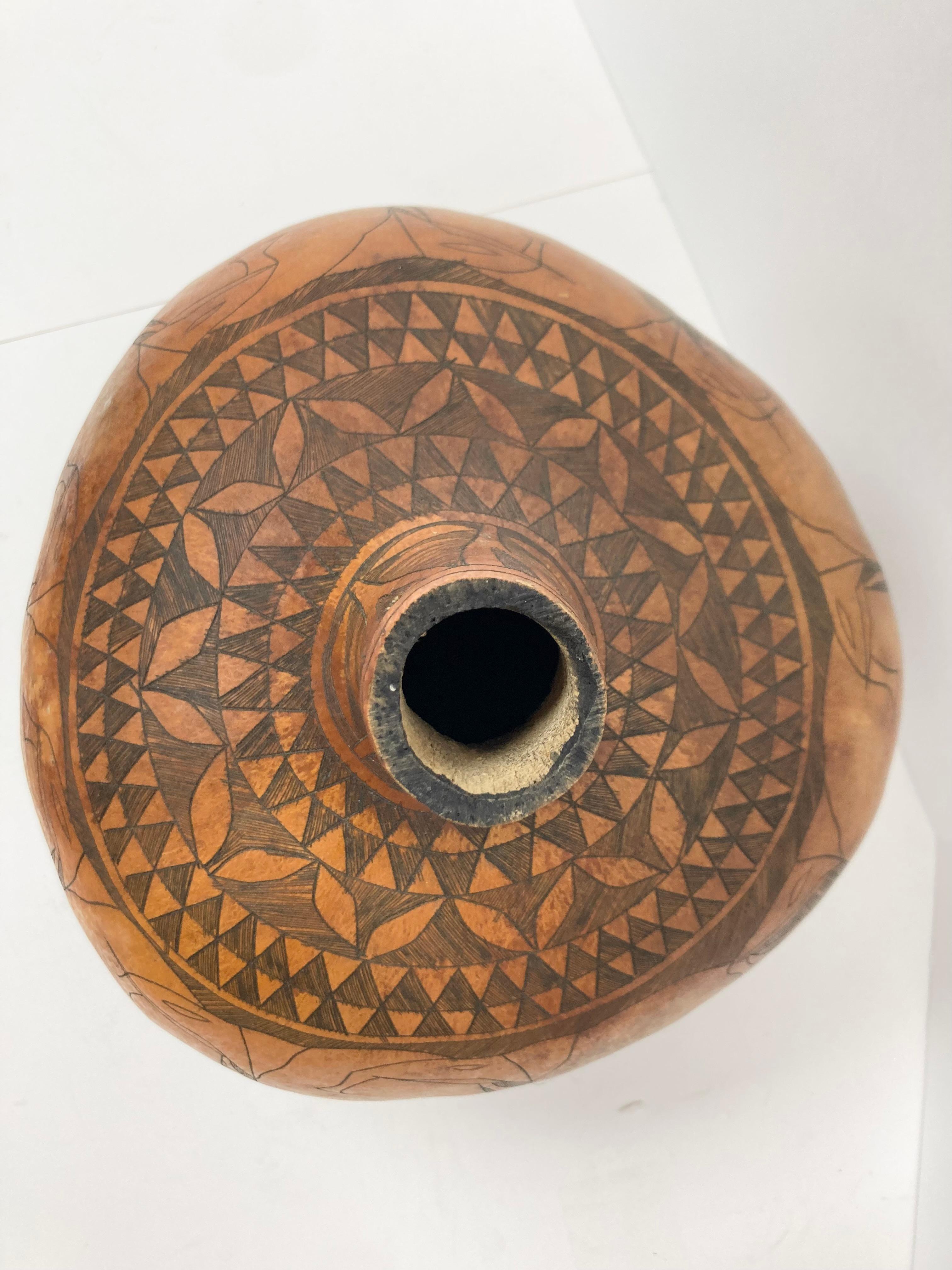 A large incise decorated Gourd from Kenya. The design is of a herd of somewhat stylized overlapping Elephants marching in single file. Delicate traditional geometric blackened incised rings surround the upper portion and lower band as well as the