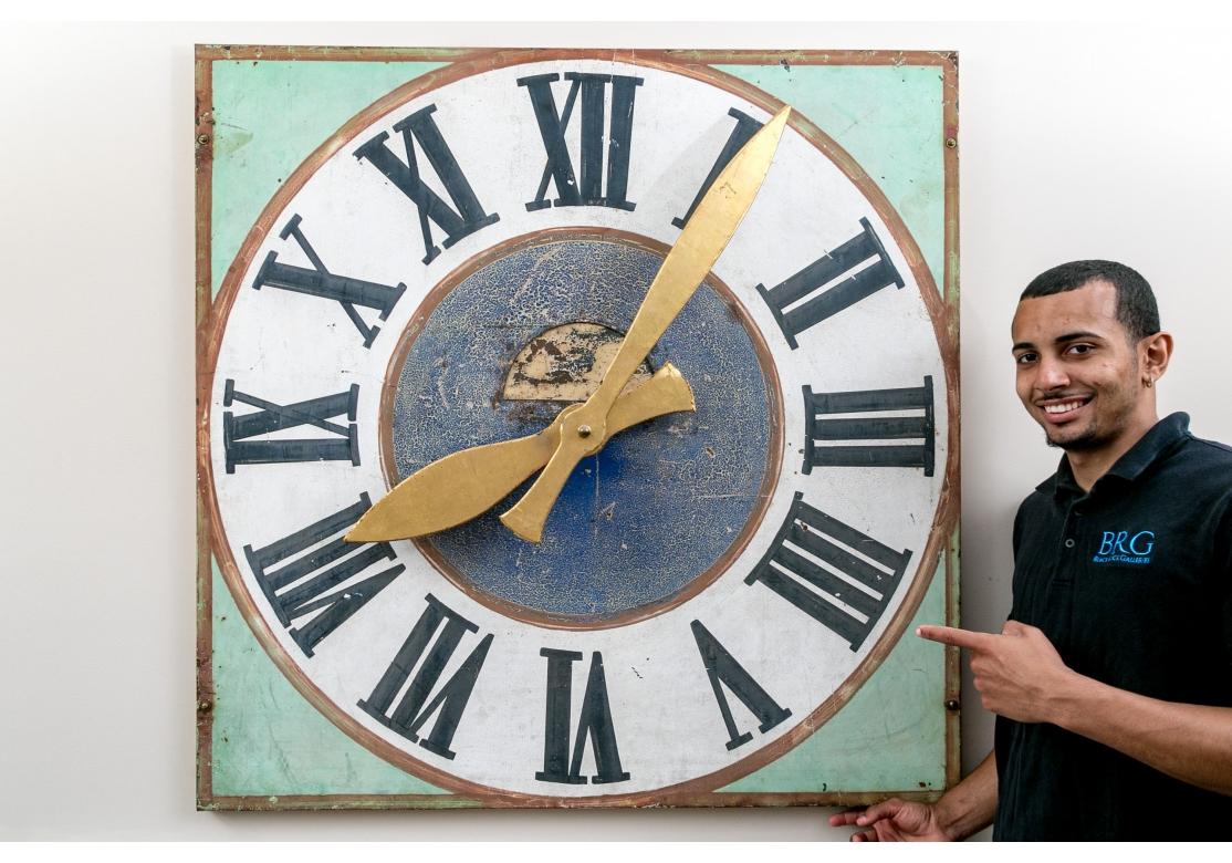 A boldly graphic and very decorative Antique Clock Face with good size and great color. An antique tower clock face on hand painted metal with Roman numerals and mounted with gilt metal handles. At an earlier time a replacement bolt to attach the