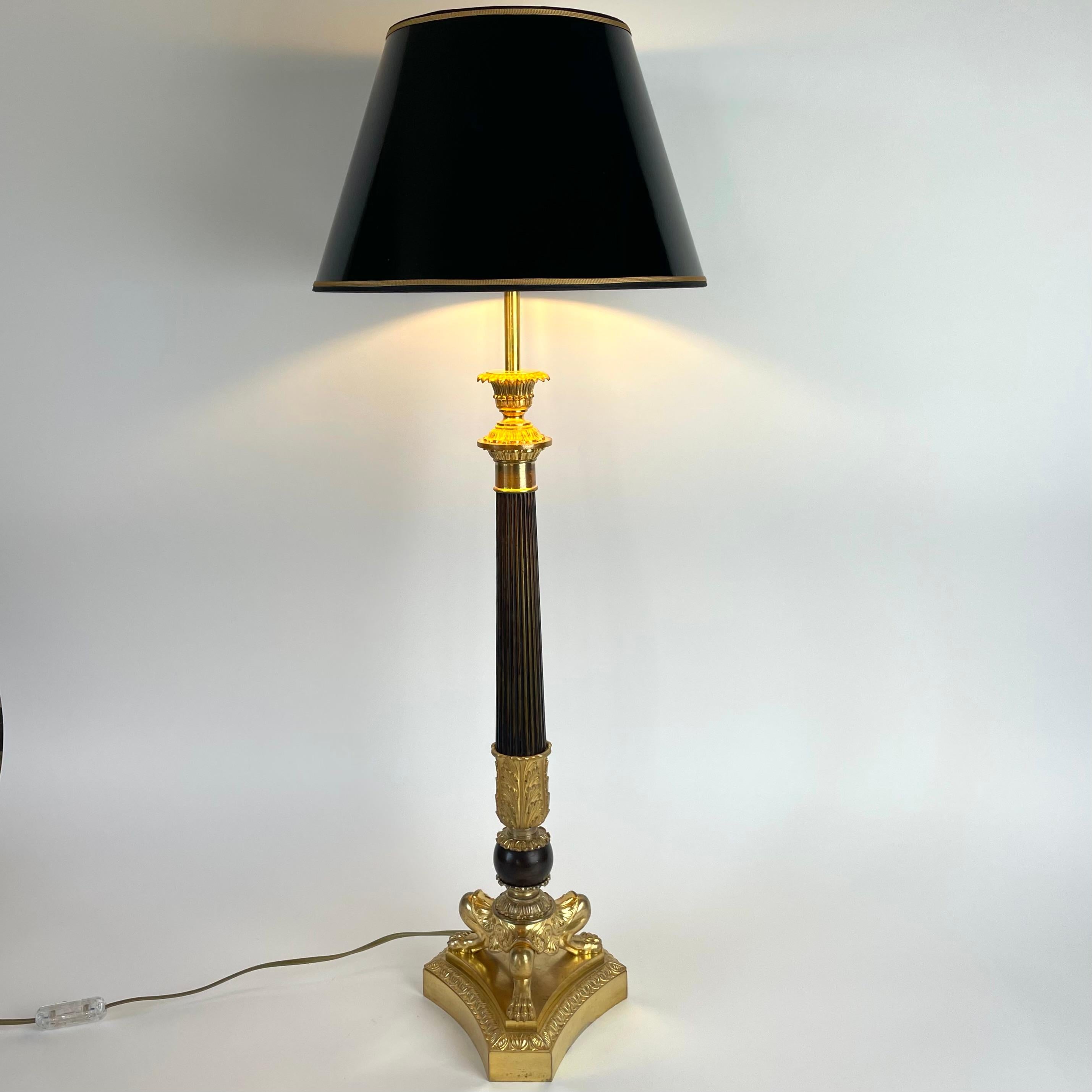 Large, beautiful table lamp of gilded and dark patinated bronze, in classic Empire style from the early 20th century. The lamp with a black lacquer shade with gold on the inside gives a  warm and cozy light.

Wear consistent with age and use 