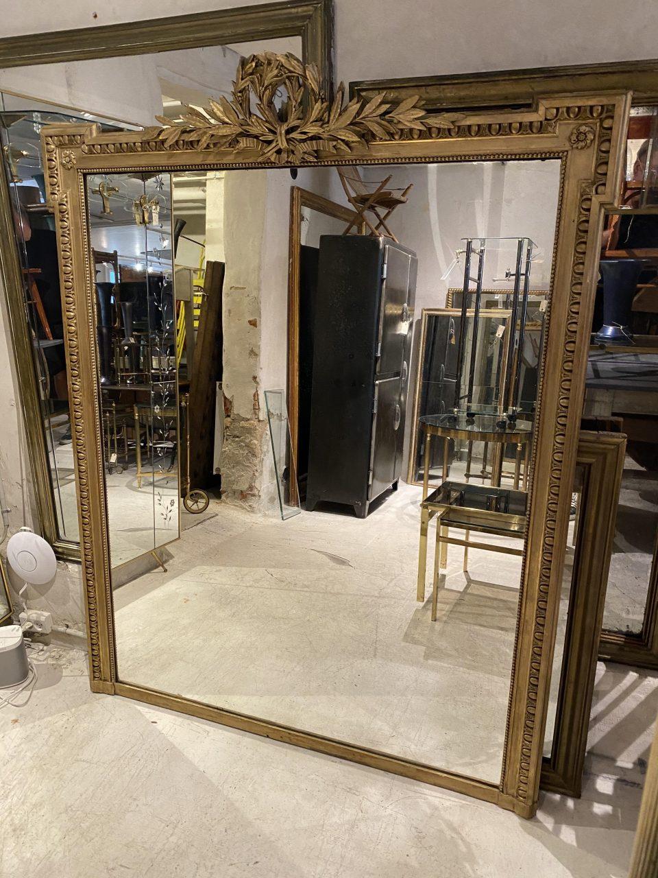 Magnificent and seldom found antique Louis Seize mantlepiece mirror, circa 1850s, France. A beautifully gilded profile frame and wonderful original patina in its mercury mirror glass.

Richly ornamented with many details, such as a double victory