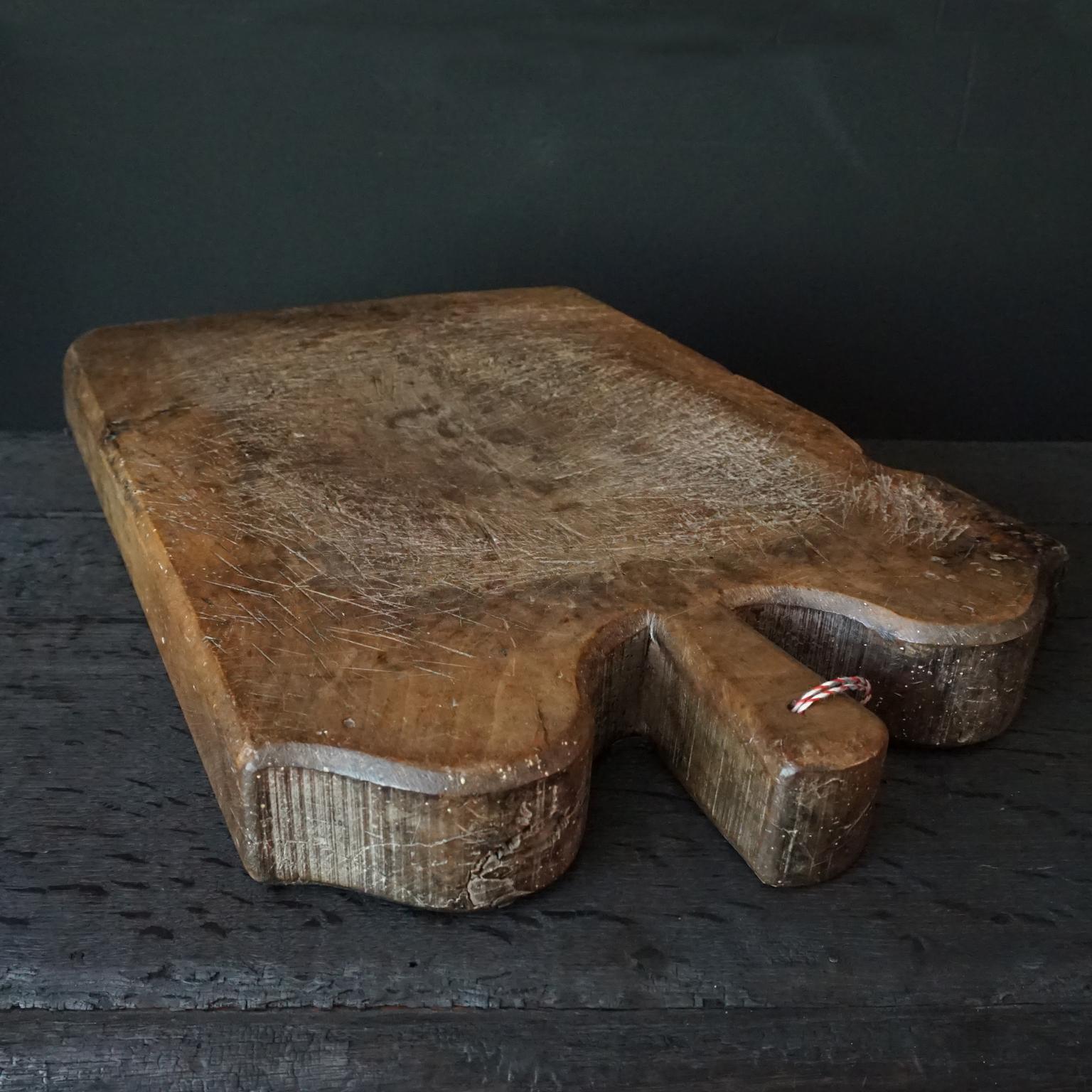 A very charming and very large 18th Century hand carved french heavy and dense fruit wood cutting or chopping board with 'shoulders'. In fact the hand carved uneven 'shoulders' make it actually look a little like a slice of bread, a large, thick and