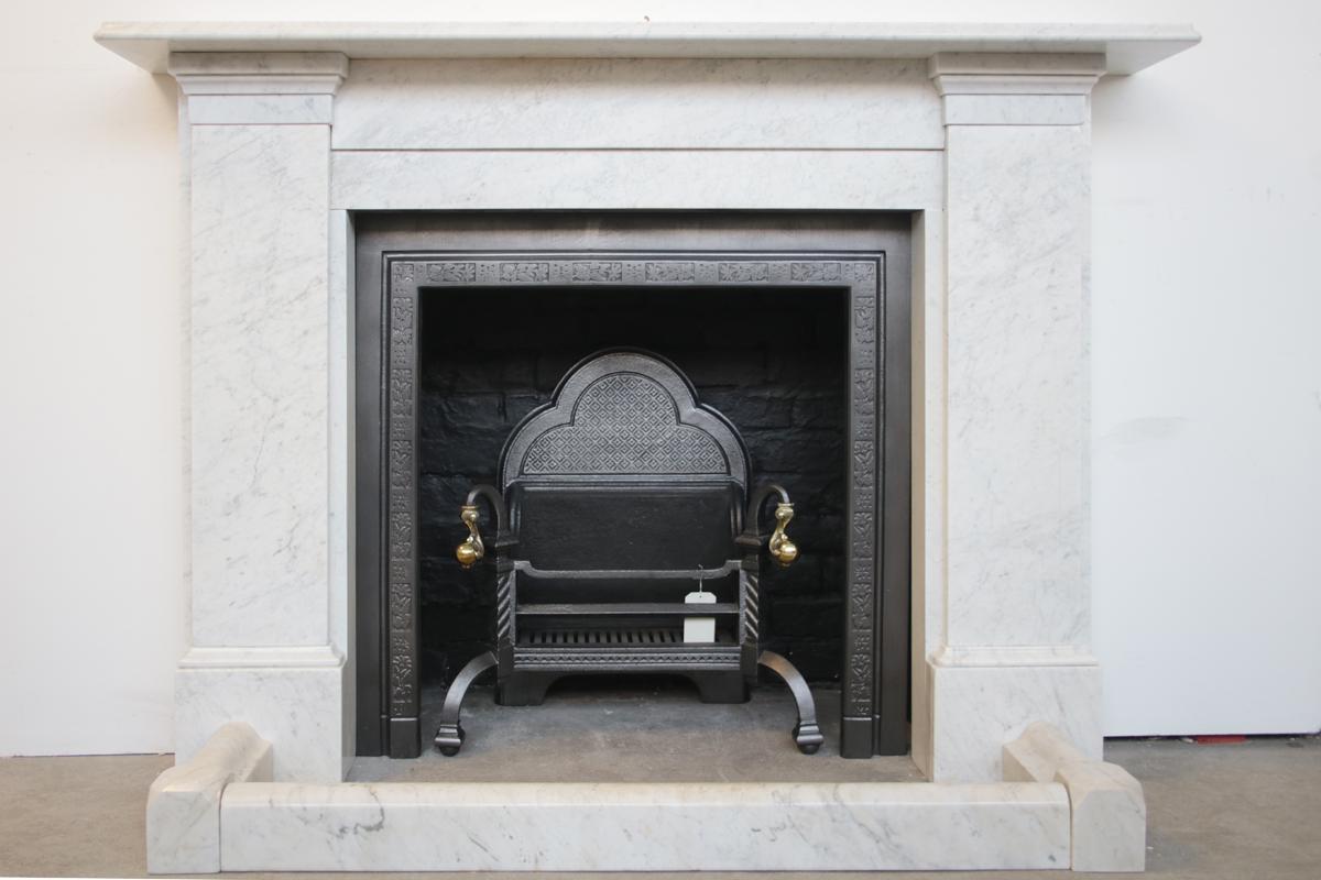 Large imposing mid-Victorian Carrara marble fireplace surround of simple form with unadorned jambs below stepped capitals supporting an ogee moulded mantle shelf, Circa 1870

Pictured with an original marble fender, cast iron frame and Victorian