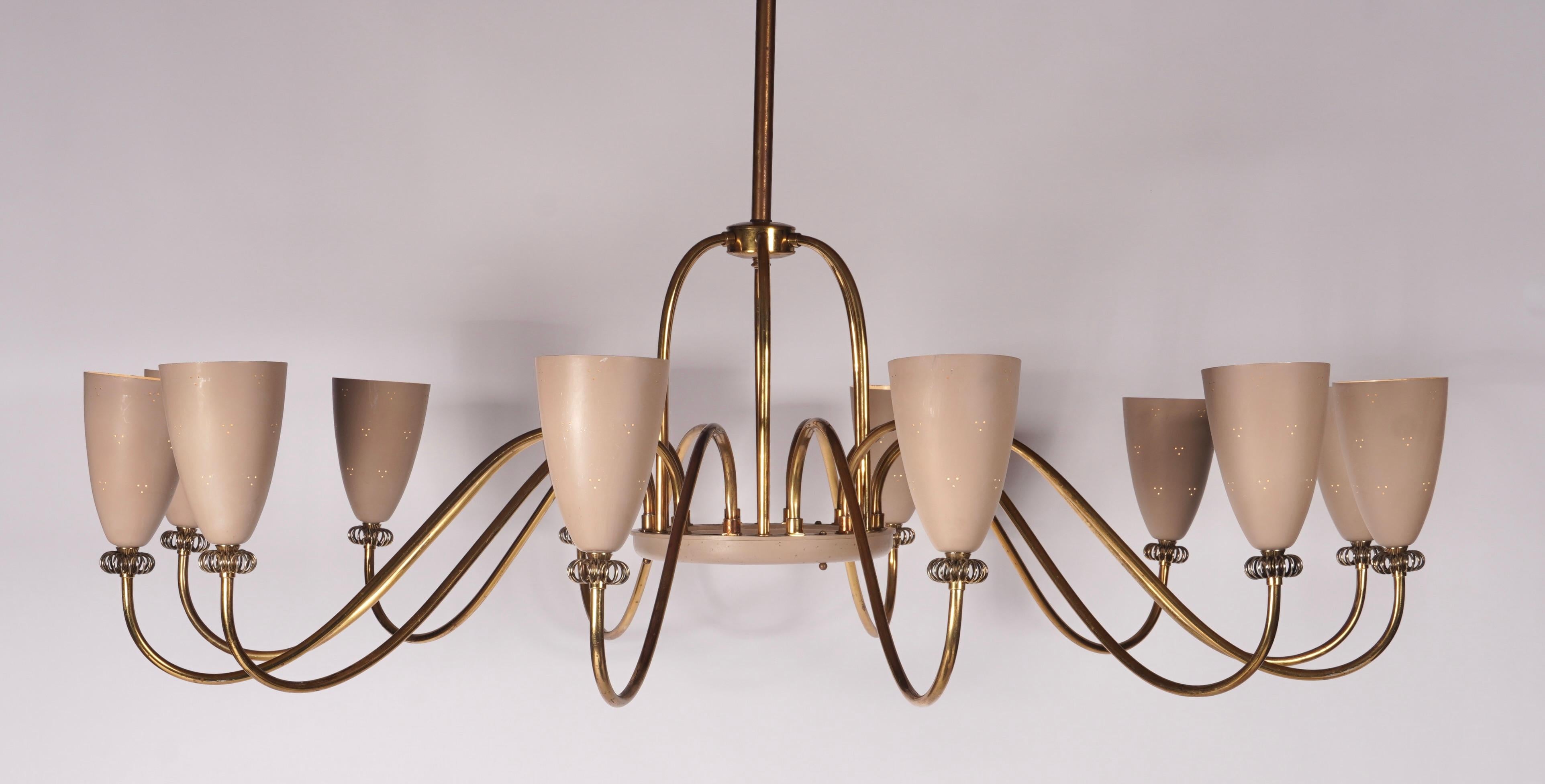 Brass and enameled chandelier by Lightoiler circa 1958, these were model 48085. Consisting of 12 pierced beige reflectors with brass arms and scroll embellishments. These were the largest in the series of the Ballerina's. The design has presence