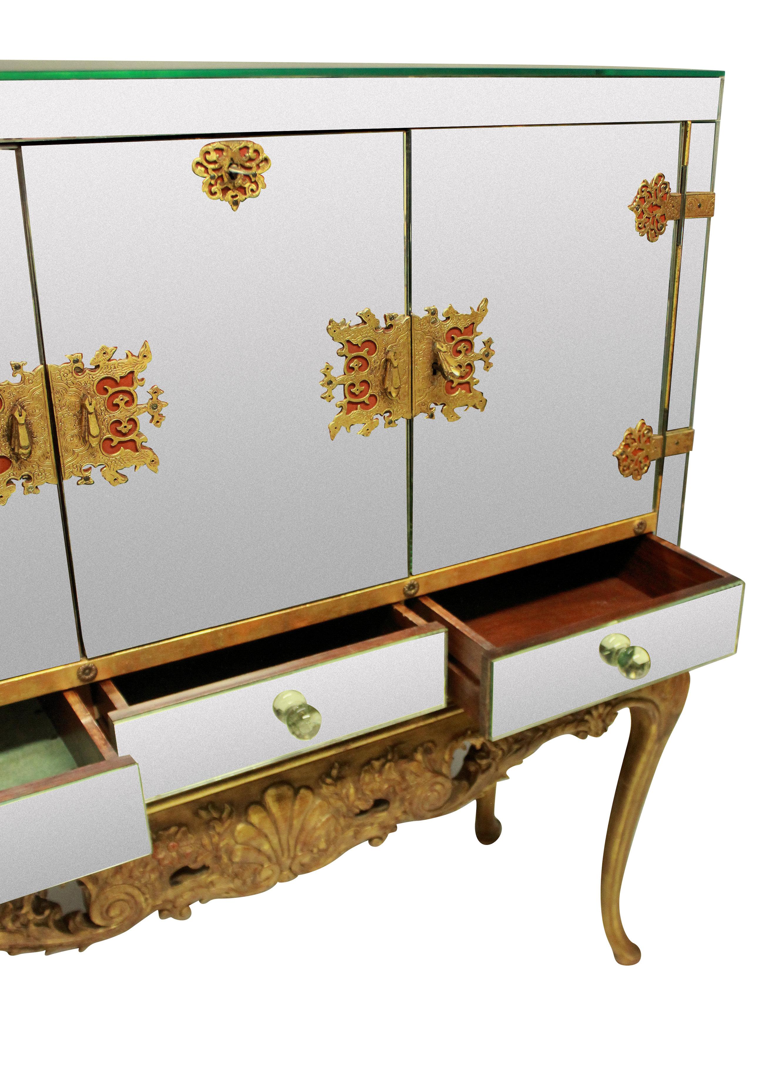 A large and impressive American bar cabinet in the chinoiserie taste. The upper section of good quality with mirror panels throughout resting upon a carved and gilded base. The intricate locks and hinges in gilt bronze with working locks and keys