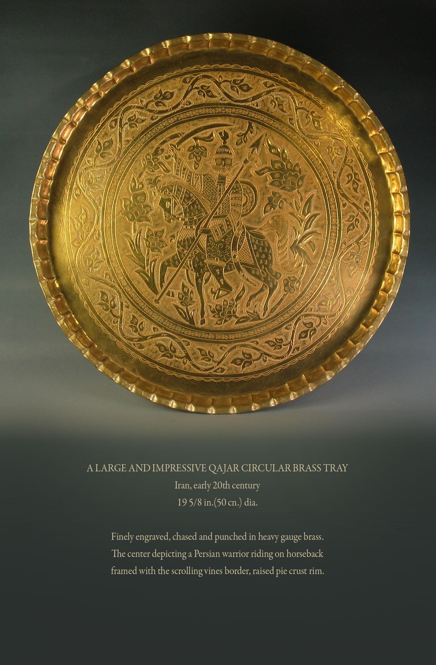 A large and impressive Qajar circular brass tray,
Iran, early 20th century.
Measures: 19 5/8 in. (50 cm.) diameter.

Finely engraved, chased and punched in heavy gauge brass.
The center depicting a Persian warrior riding on horseback
framed