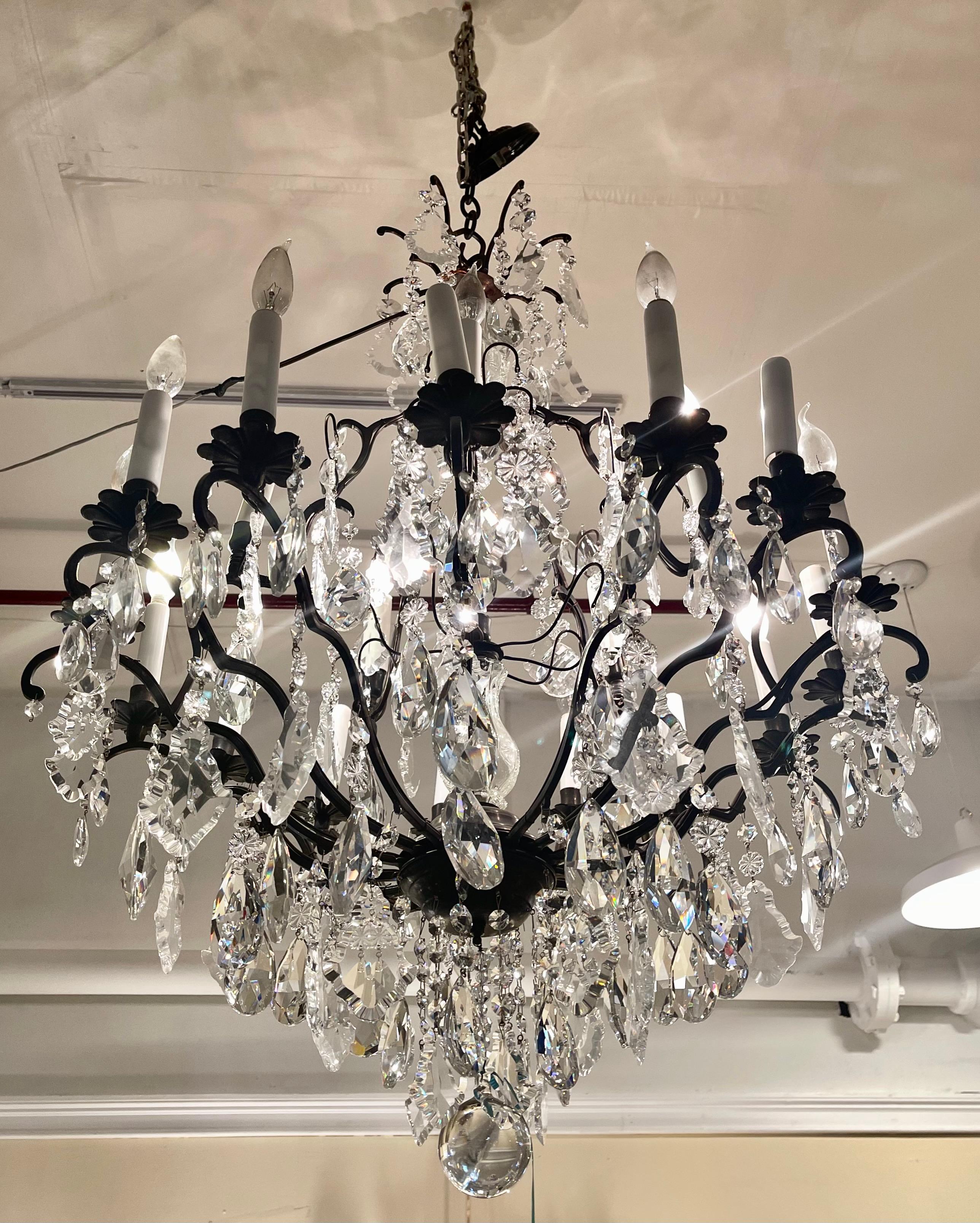 A large and impressive Versailles metal and crystal chandelier. Having antiqued bronze and Czech cut crystals this recently re-wired twenty light chandelier is sure to light up any foyer or dining room it is placed in. The whole of paint decorated