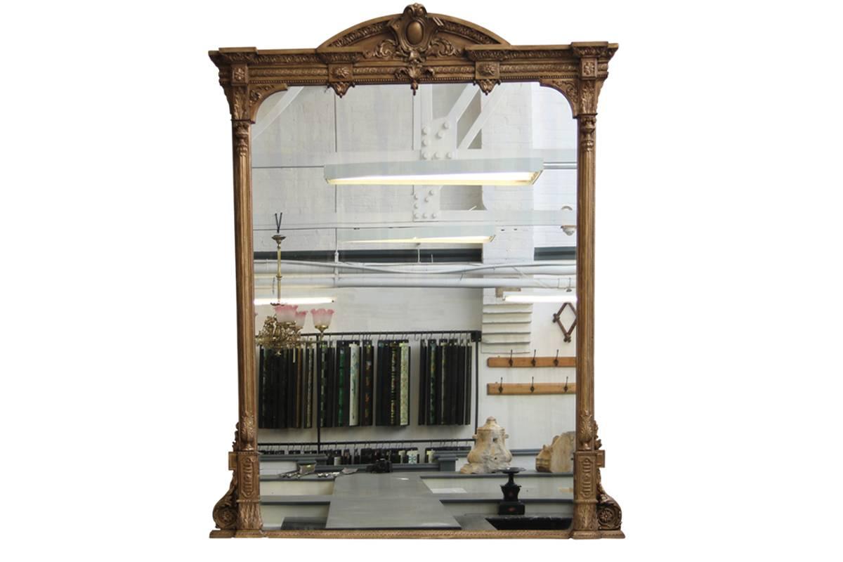 A large and impressive Victorian giltwood and gesso over mantel mirror. The impressive domed arched break front cornice decorated in bold relief with acanthus, guilloche and scrolling foliage above the mirrored plate, flanked on either side by