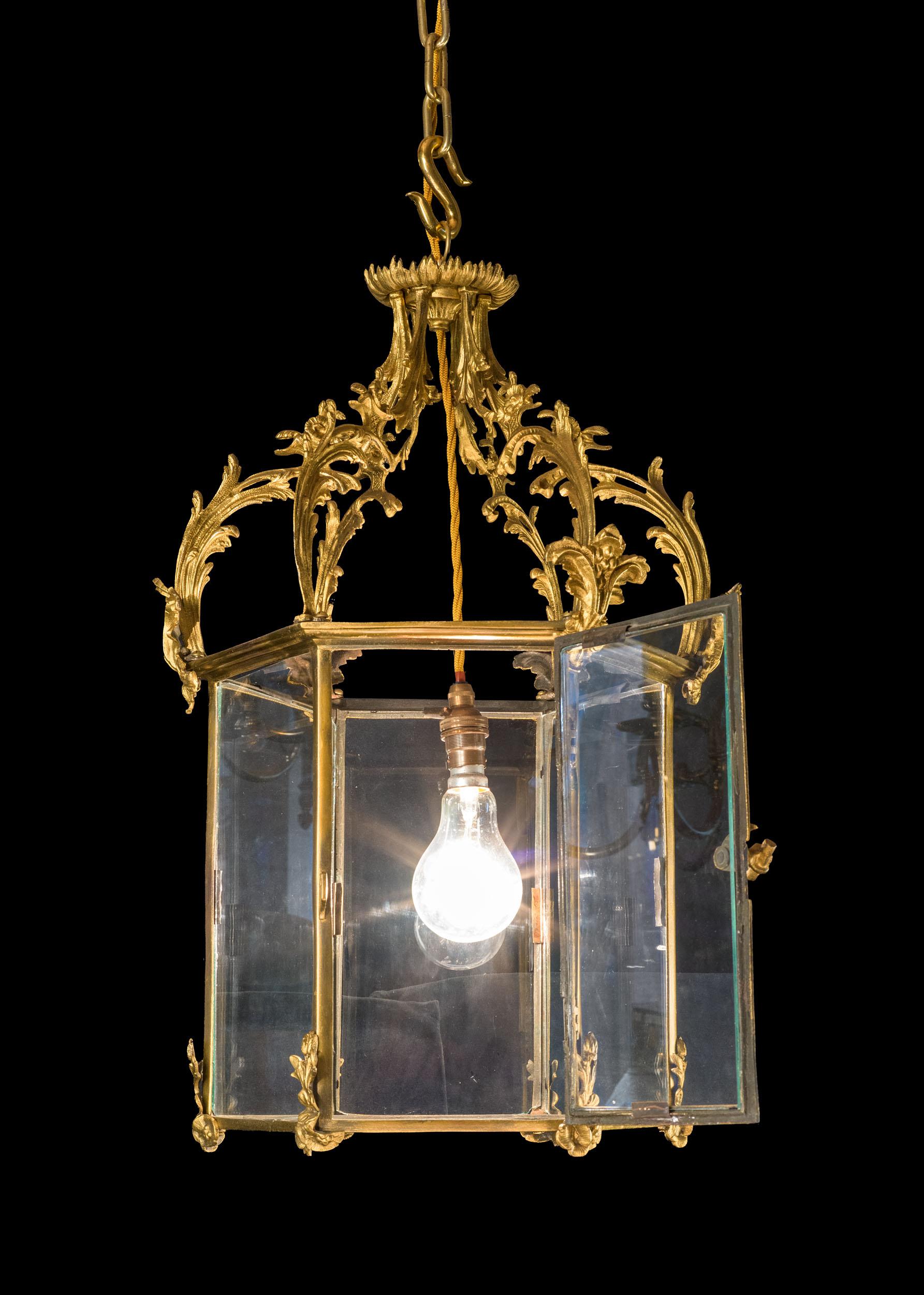A large and beautiful Régence style hanging lantern. The hexagonal glazed lantern is mounted with an ornate foliate corona, with traces of the original gilding. The hinged door has the charming feature of very small handle modelled as a
