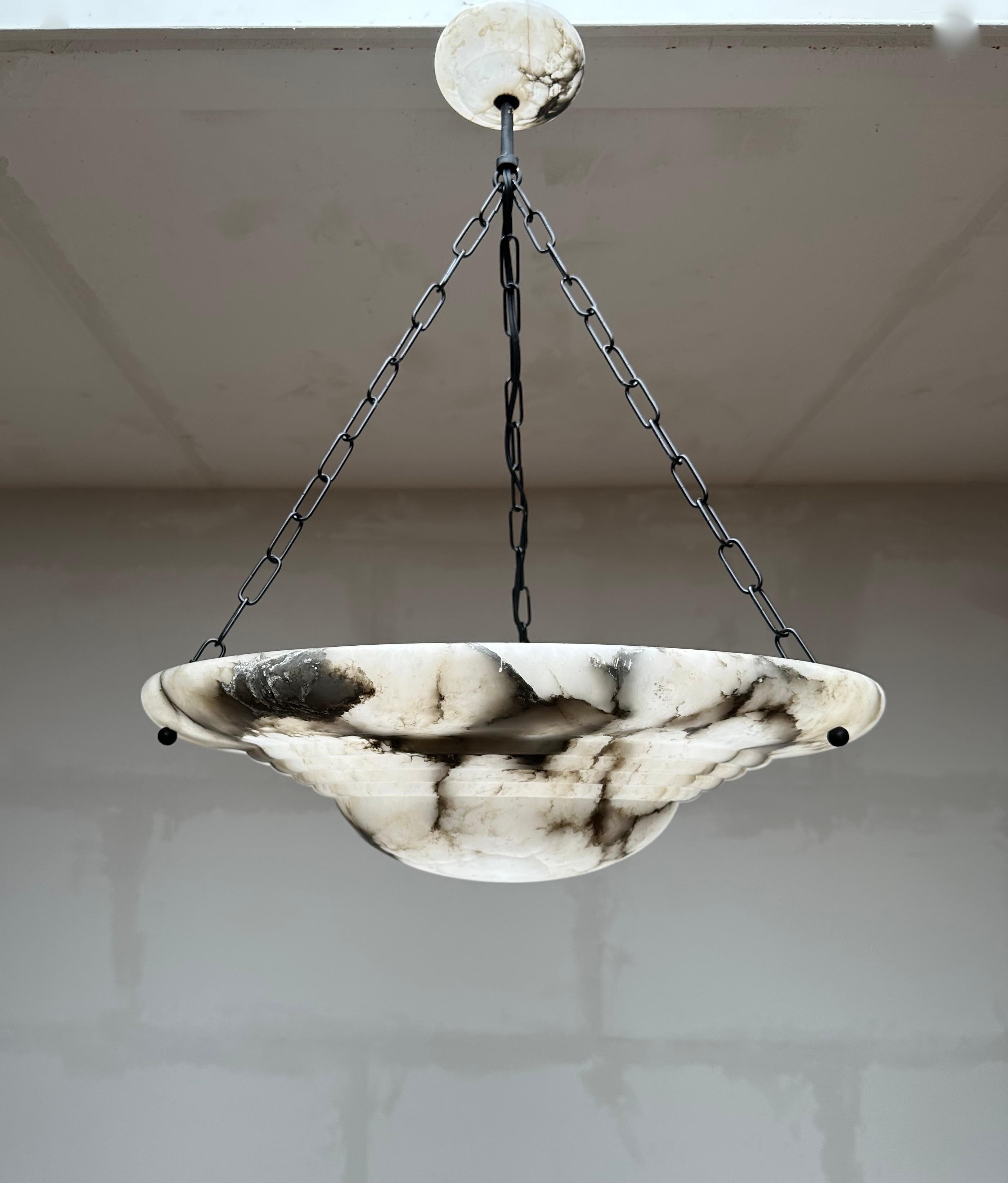 Stunning and large alabaster pendant of great quality, 1910s.

This rare fixture from the heydays of the European Art Deco era will light up both your days and evenings. Its remarkable, circular and layered shade is all hand carved out of one solid