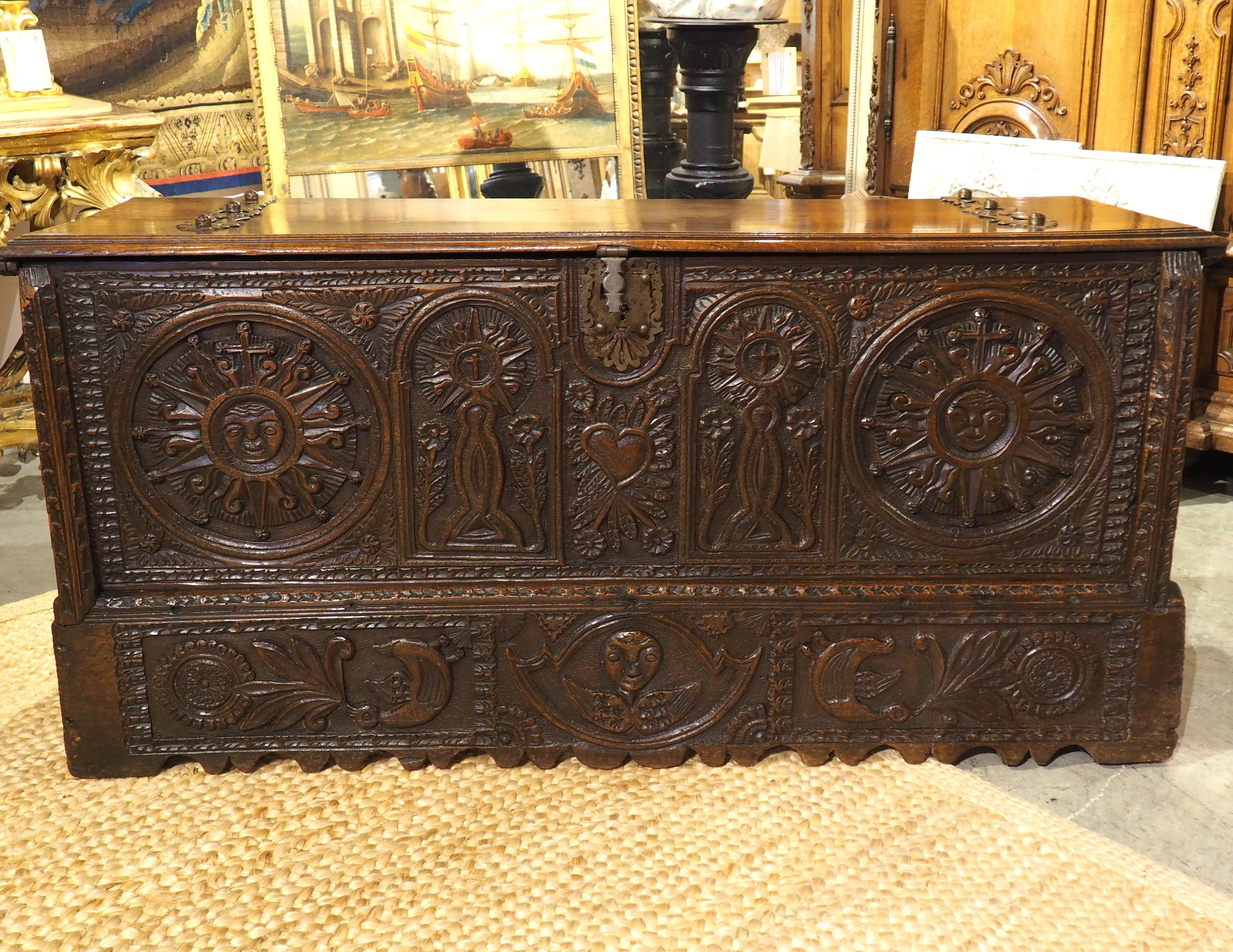 A beautiful and robust Spanish trunk, the carvings on the front façade are large and vibrant, accented by a deep brown patina. The trunk was hand-carved in the 1600s by a master craftsman, using both oak and walnut woods. Large dovetail joineries,