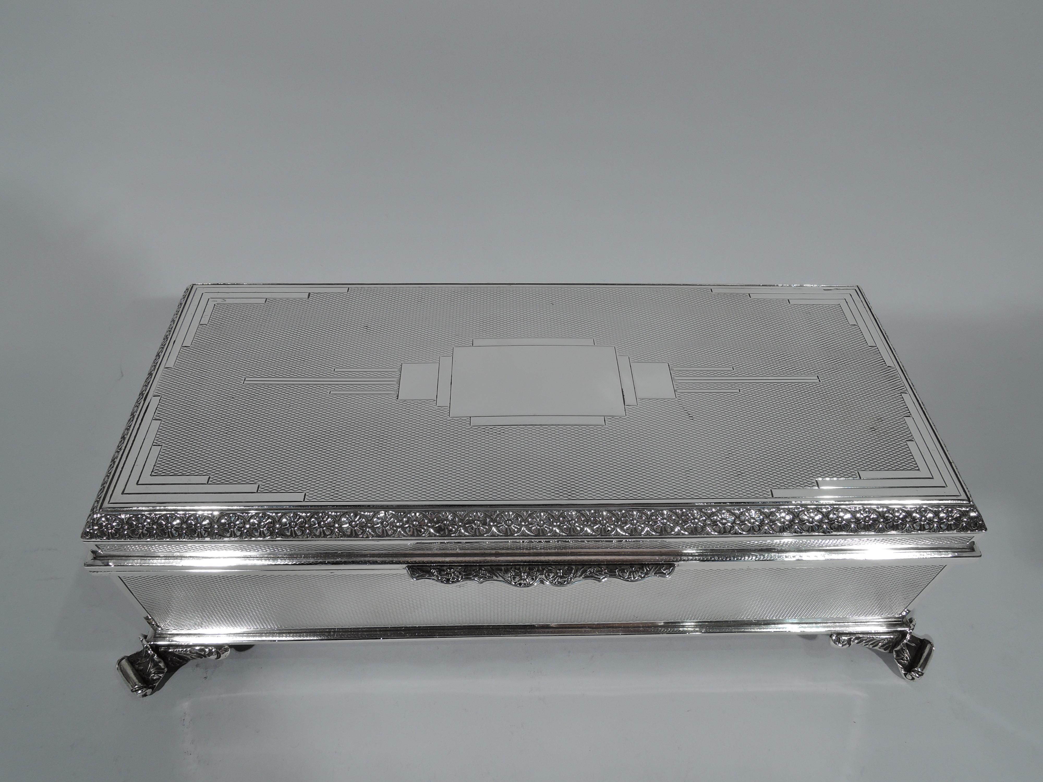 Large and striking Art Deco sterling silver box. Made by AE Poston & Co., Ltd in Birmingham in 1933. Rectangular with straight sides and spread and stylized leaf-mounted volute-scroll corner supports. Cover hinged and raised. Allover engine-turned