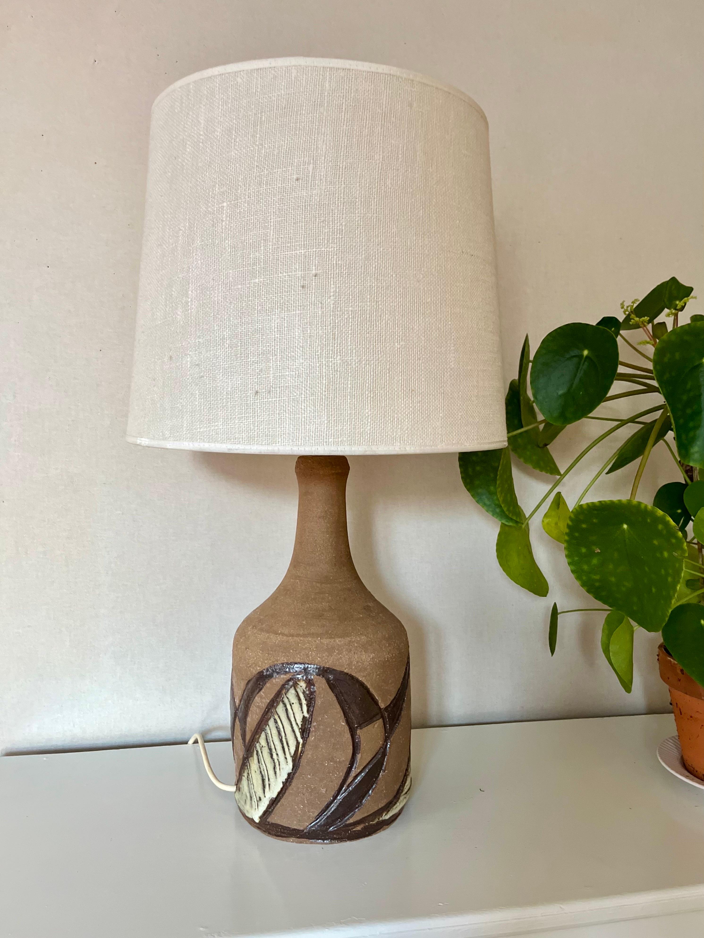 Large and Tall Danish Brutalist Ceramic Table Lamp, 1970s

Striking Danish Brutalist ceramic table lamp from the 1970s. The base is crafted from matte stoneware with organic decorations that are engraved and glazed in dark brown and cream tones. A