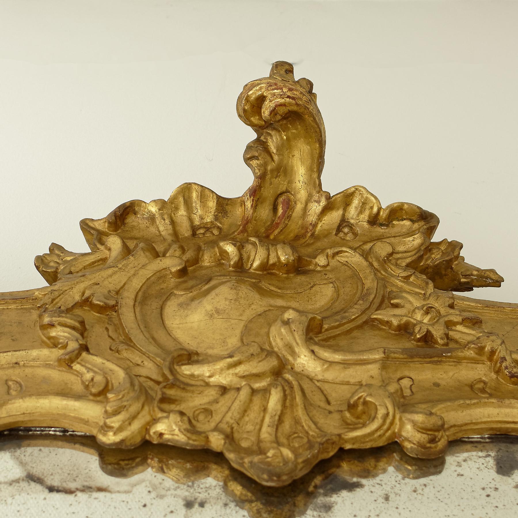 The large and very decorative mirror with a shaped rectangular divided plate, within an elaborately carved frame embellished with C-scrolls, rocaille and foliage, surmounted by a conformingly decorated whimsical rocaille cresting set with a further