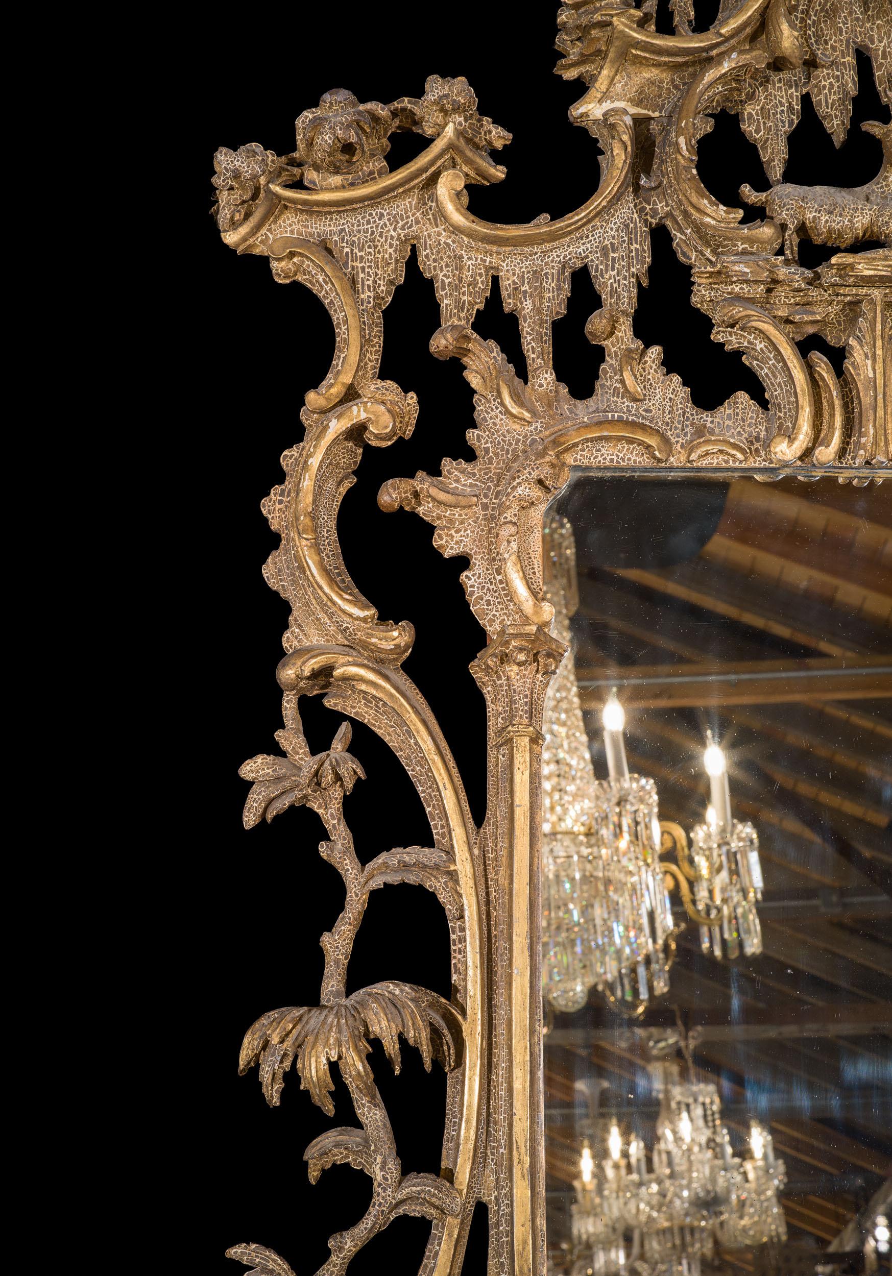 A grand giltwood wall mirror in the manner of Thomas Johnson with a Rococo frame comprising c scrolls and foliate flourishes and surmounted by a ho-ho bird. A detail typical of Thomas Johnson is the inclusion of an animal, and here a goat teeters on
