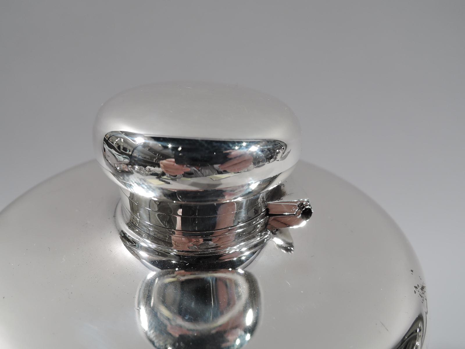 Large and unusual sterling silver flask. Made by Tiffany & Co. in New York, circa 1910. Truncated cone; gently curved and overhanging top with hinged and cork-lined bun cover. A big game-era vessel for passing around the campfire. Wide hand span