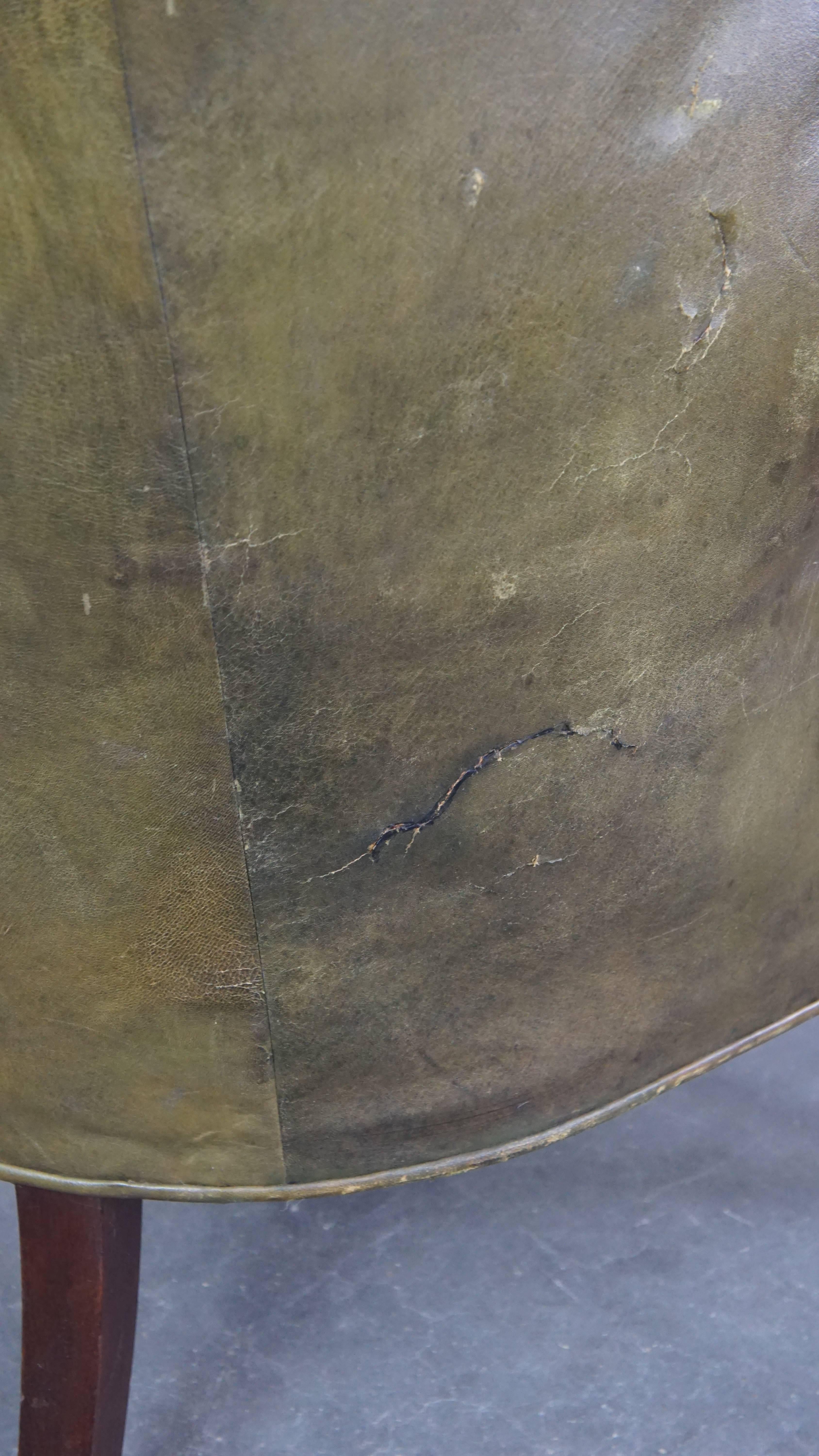 Large and well-worn green antique leather barrel-back armchair on wheels For Sale 4