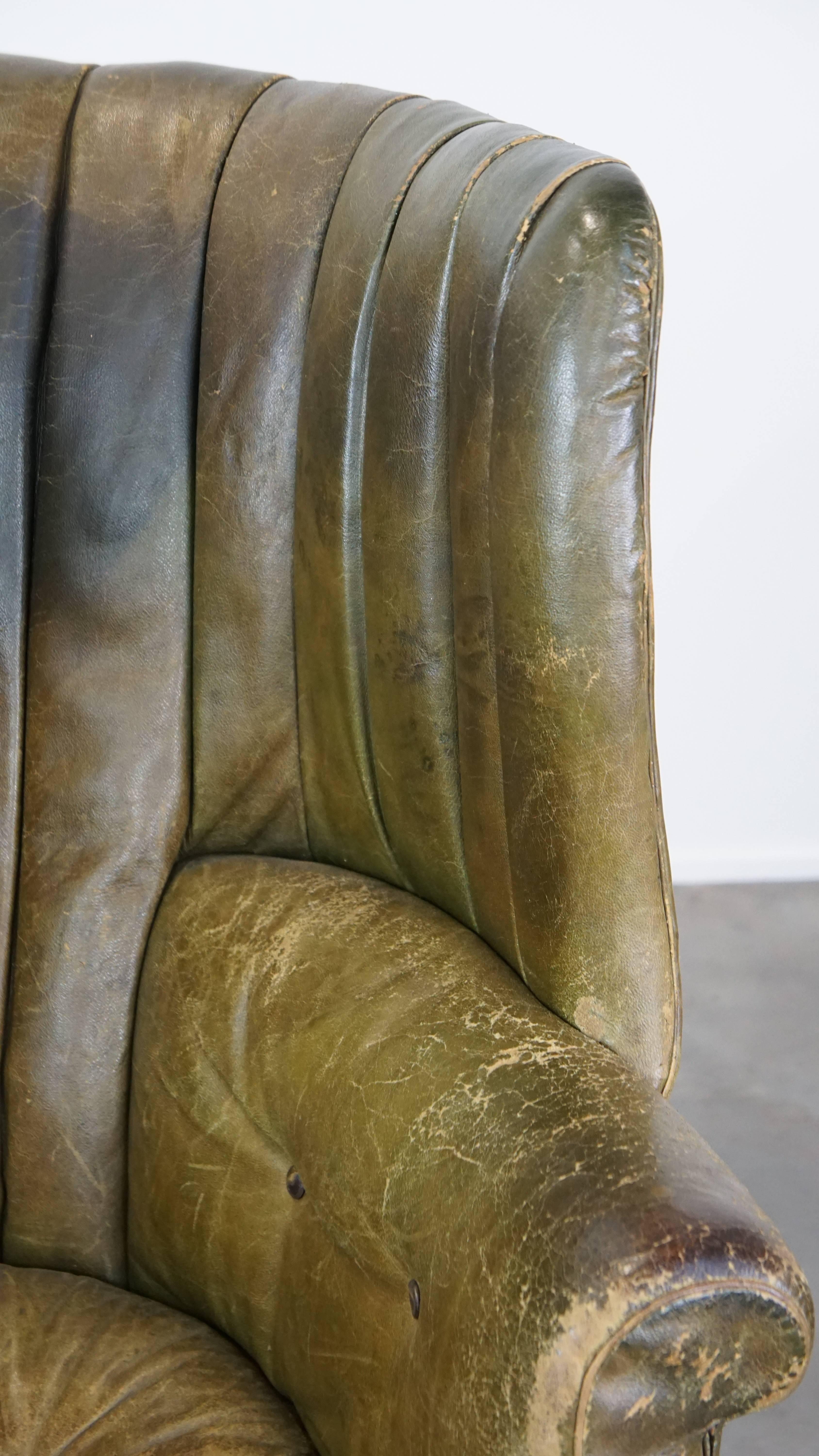 Large and well-worn green antique leather barrel-back armchair on wheels For Sale 7