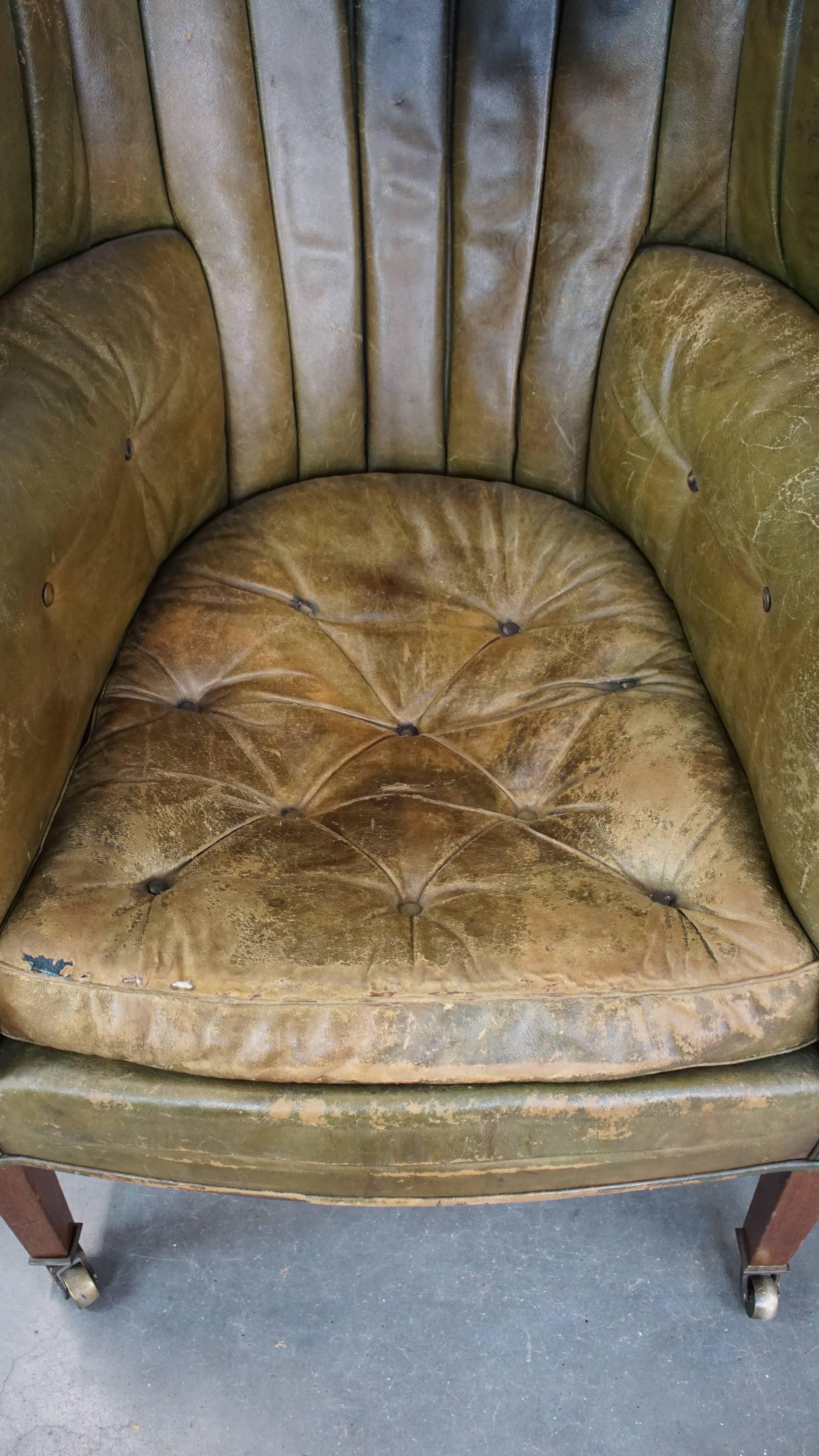 Leather Large and well-worn green antique leather barrel-back armchair on wheels For Sale