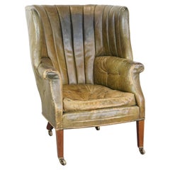 Large and well-worn green Antique leather barrel-back armchair on wheels