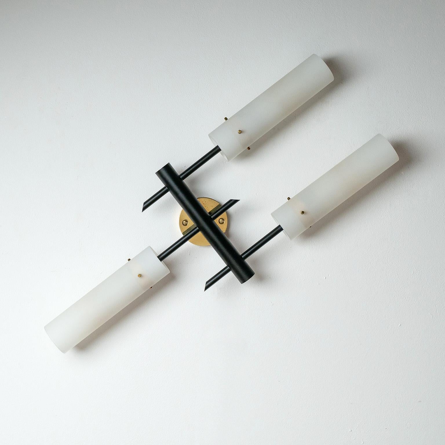 Rara applique modernista a tre bracci di Angelo Lelii per Arredoluce degli anni Cinquanta. Struttura interamente in ottone, parzialmente laccata in nero, con tre sottili tubi in vetro satinato. Condizioni originali molto buone con patina minima. Tre
