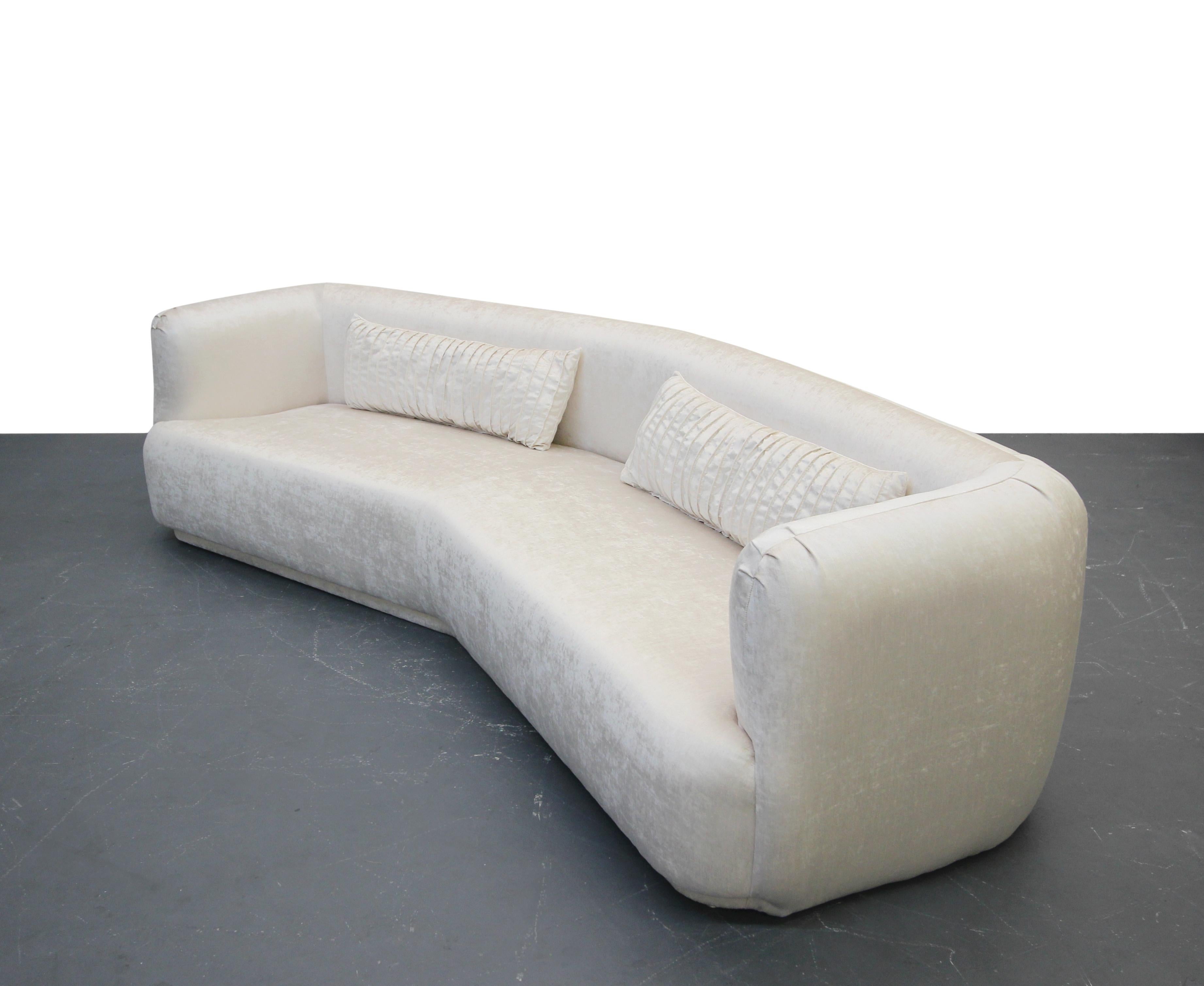 Freshly reupholstered in a beautiful cream color, high quality velvet, this beauty is dressed to impress. Angled sofas are rare, and to find one with these round edges is basically impossible. Stunning pieces, completely restored and ready for its