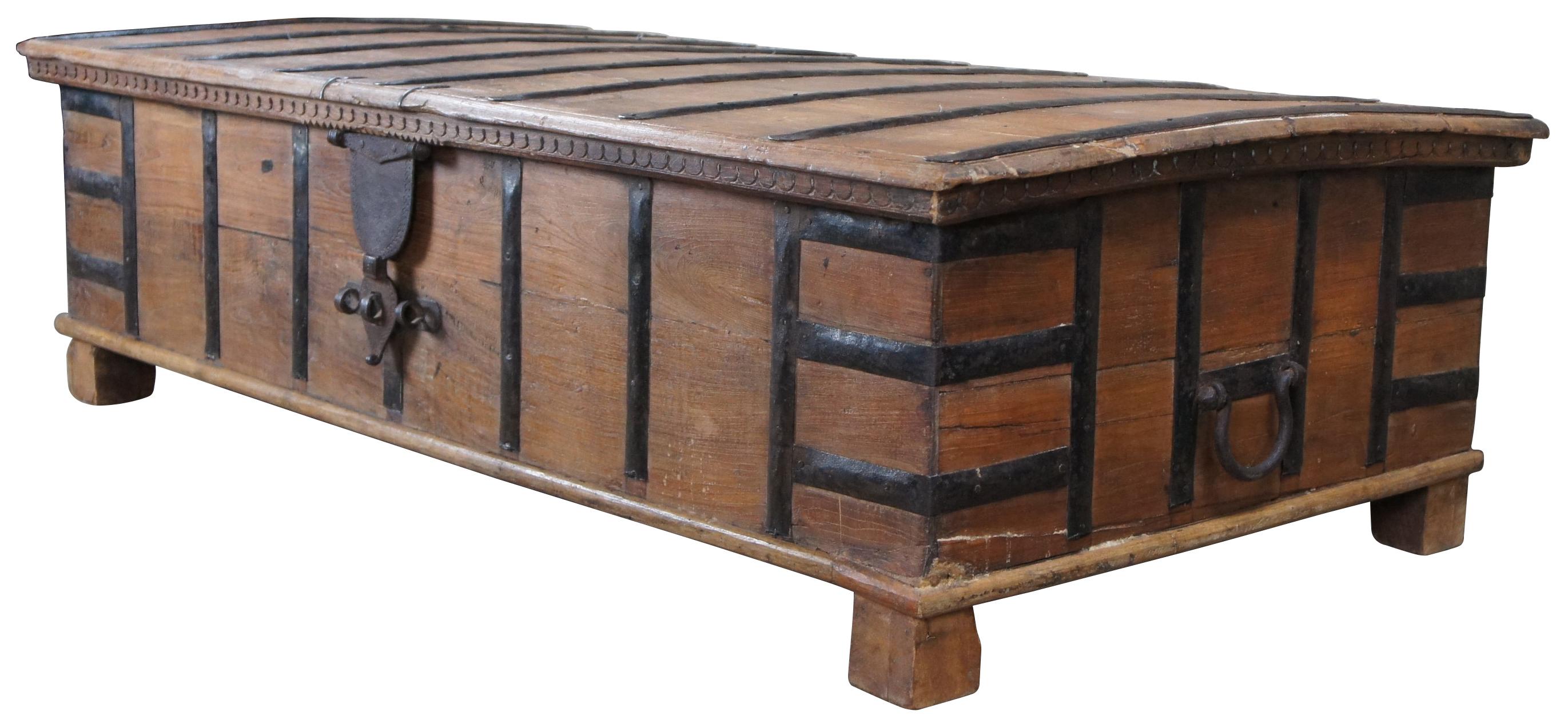 Beautifully detailed 20th century Anglo-Indian storage trunk coffee or cocktail table.  A rectangular form made from reclaimed teak with iron banding.  The top shocases a slight dome top with a carved apron.  Includes ornate latching and handles