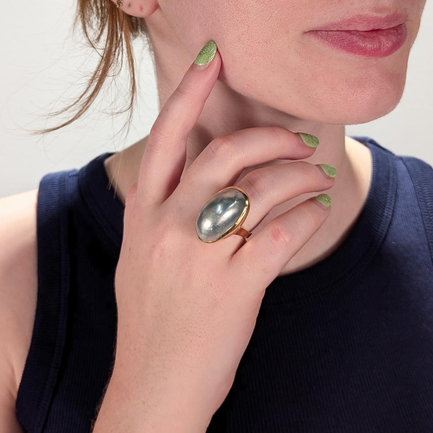 A fine vintage cocktail ring.

In 14 karat yellow gold.

Set with a large silver-gray mabe pearl in a deep bezel setting.

Supported by a robust shank with split shoulder.

Marked 14K to the interior shank and with a maker's mark or hallmark to the