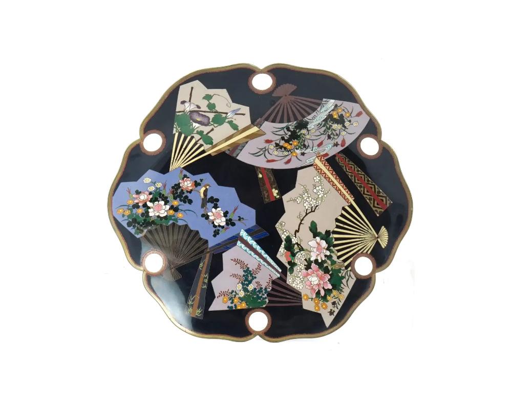 An antique Japanese, late Meiji era, enamel over gilt copper plate. The interior of the plate is adorned with polychrome enamel figural medallions depicting fans with birds, blossoming flowers, and sakura trees on the black ground made in the