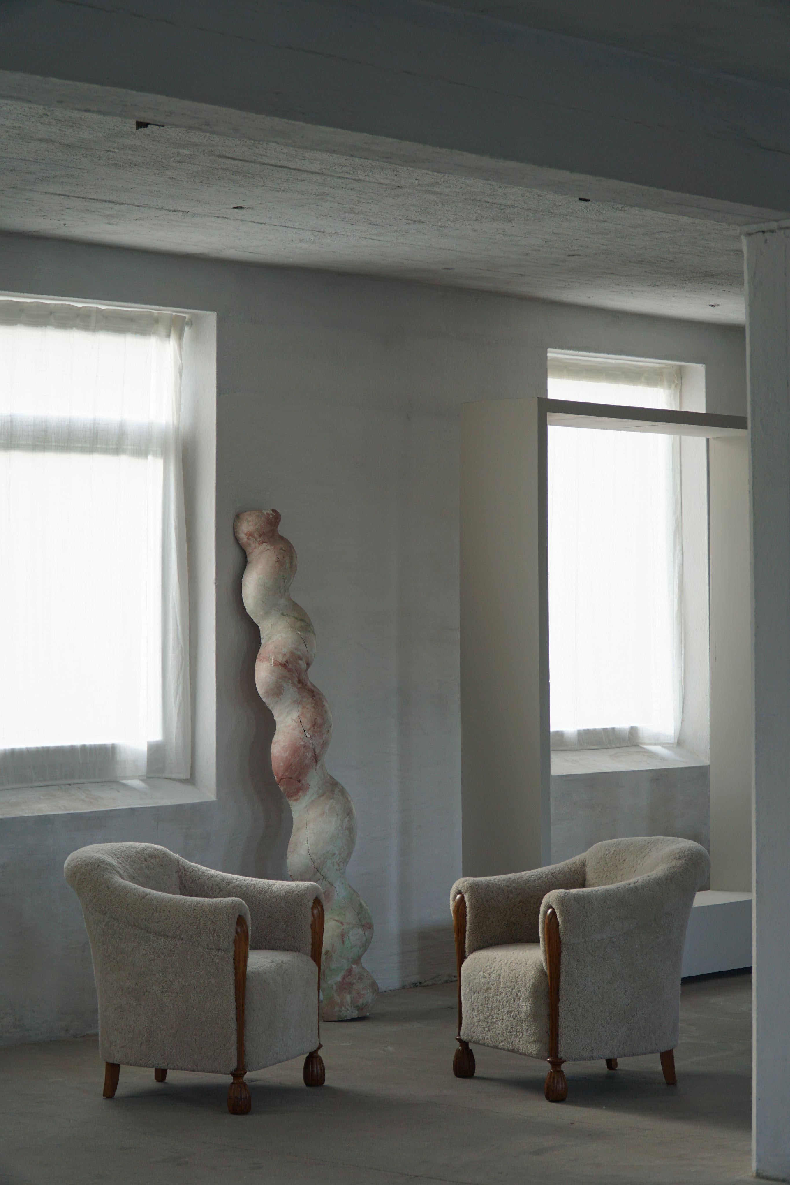 A striking hand-carved wooden sculpture, nearly 200 cm tall, with a twisted form that evokes organic movement and architectural rhythm. Painted in delicate layers of soft pink, green, and white tones, the surface has a marbled, fresco-like quality