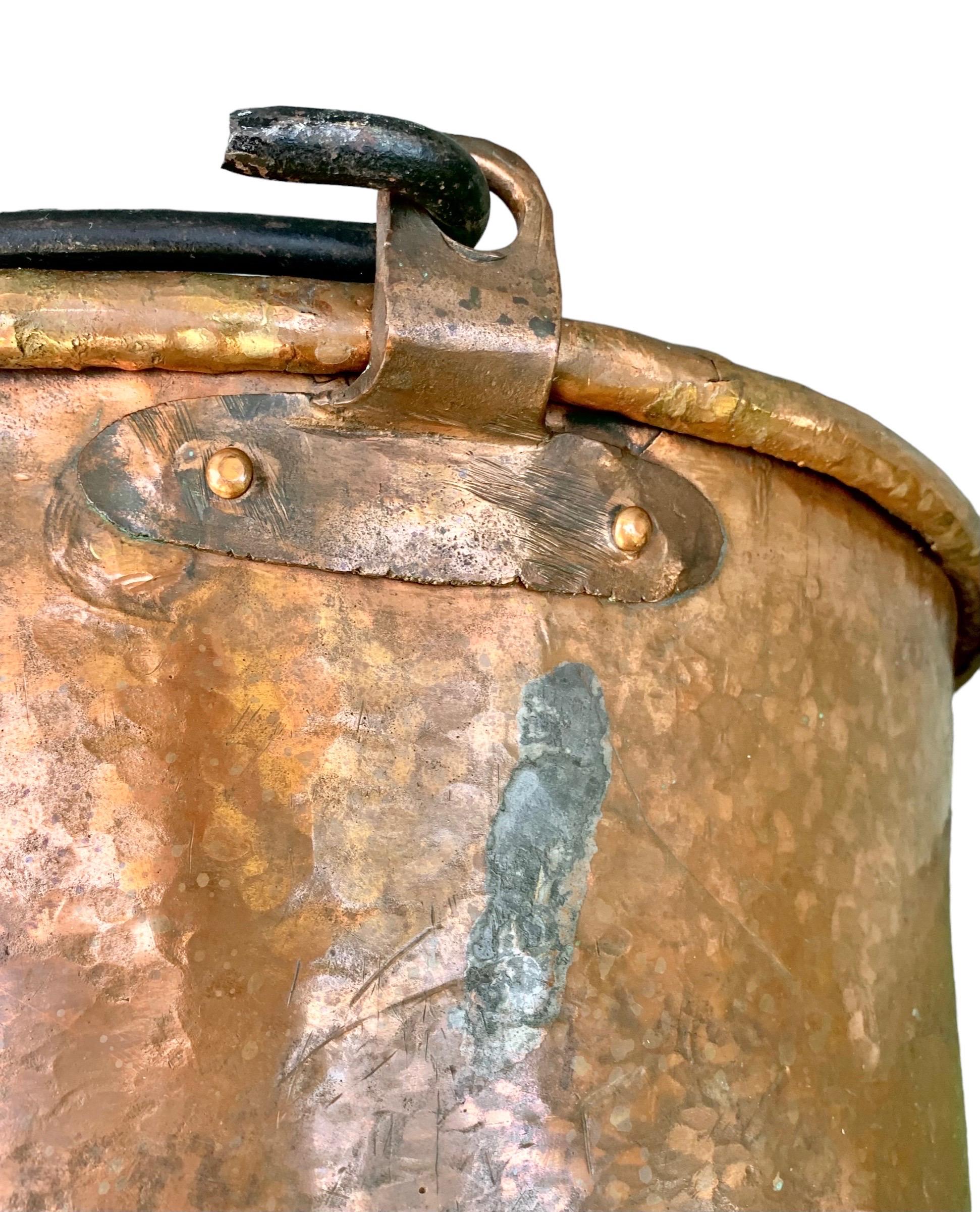 A large early 19th c., French Provincial hammered copper cooking pot/ cauldron with a riveted iron swing handle and hand rolled rim with an extraordinary old finish/patina.
Although I have not detected any markings, this piece was beautifully